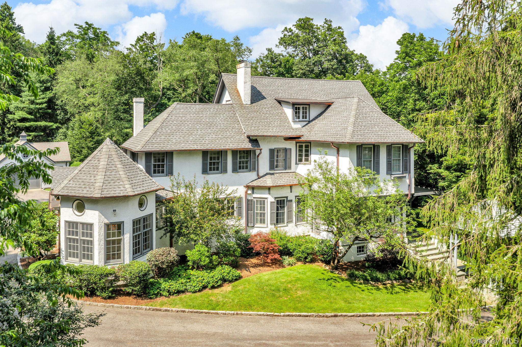 Timeless elegance meets modern comfort in this enchanting 1901 hunting lodge, masterfully restored in 1991 and recently enhanced. Set on beautifully landscaped grounds with lush gardens, this distinguished home features a dramatic front portico, high ceilings, intricate millwork, and unique architectural details throughout. Grand living spaces include a library/home office with French doors and fireplace, a formal living room with built-ins, fireplace, and terrace access, and a dining room with fireplace that opens to a sun-drenched three-season room. The custom chef’s kitchen features a center island, marble countertops, high-end appliances, and an adjoining octagonal breakfast room with cathedral ceiling and clerestory windows. A family room and mudroom/laundry with garage and yard access complete the main level. Upstairs, the spacious primary suite offers a walk-in dressing room and spa-like bath. Additional bedrooms include one with ensuite bath and walk-in closet, one with a fireplace, and one with built-ins. The finished third floor offers a bedroom, full bath, and flexible bonus room. Additional highlights include updated mechanicals, a 17kW whole-house generator, a detached garage, and numerous enhancements made over the past few years. A rare opportunity to own a truly special home filled with character, comfort, and timeless style in a prime location.