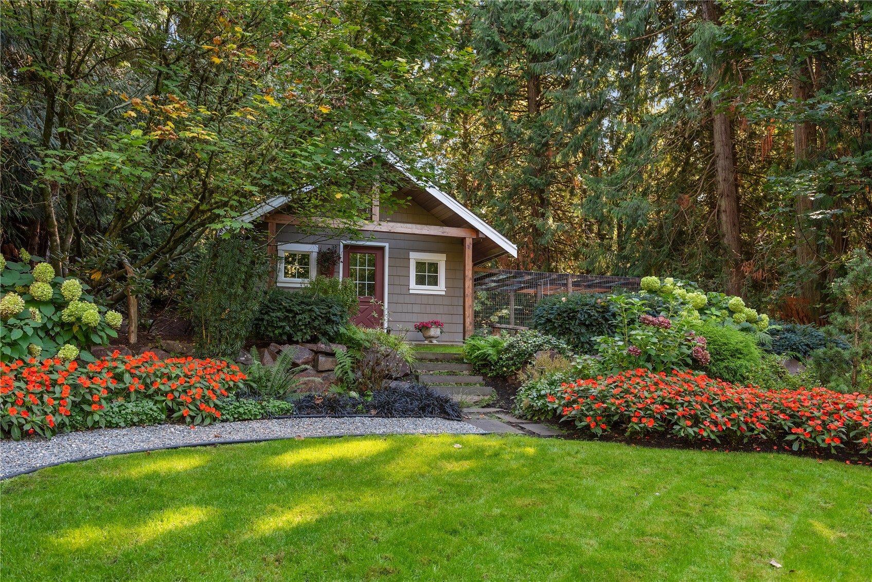 Garden shed with red door surrounded by flowering landscape