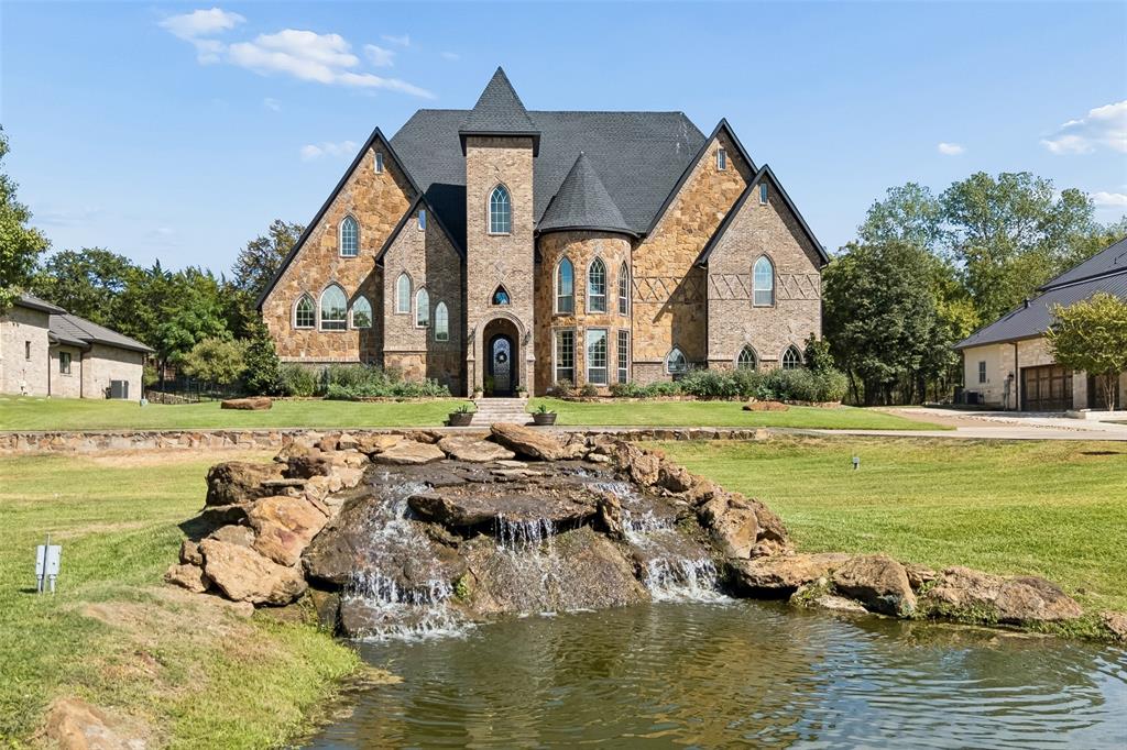 Set on 1.15 acres in a private, gated setting, this exceptional Southlake residence blends remarkable architecture, grand interiors, and resort-inspired outdoor living. Step inside to soaring ceilings, rich hardwood floors, substantial stone accents, and a sweeping wooden staircase rising to a curved second-story balcony. Impressive multi-pane windows fill the living room with natural light, while a floor-to-ceiling stone fireplace creates a dramatic focal point. The kitchen continues the home's architectural character with a cooktop framed by an impressive arched stone hearth alcove. A dedicated office with its own fireplace offers an inviting setting for work or study. The primary suite provides a private retreat with a castle-inspired bath. Each bedroom includes its own full bathroom, while two secondary bedrooms feature built-in loft spaces that add charm and versatility. Outdoors, the property unfolds into a resort-inspired escape. A custom in-ground pool with bubbler fountains is paired with an elevated stone hot tub that spills into the pool. The adjoining covered patio extends the living and entertaining space with stone arches, a soaring fireplace, and an outdoor bar and kitchen. Four ponds add beauty and character to the surrounding grounds. Convenient access to Southlake Town Square, area shopping, dining, recreation, and DFW International Airport keeps everyday destinations within easy reach while preserving a sense of privacy at home. Schedule a private showing to experience the architecture, setting, and indoor-outdoor lifestyle firsthand.