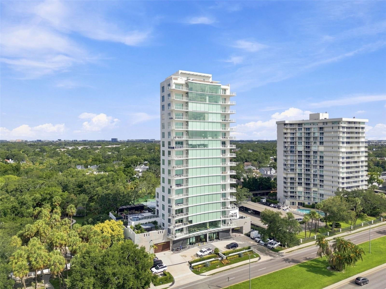 Set above famed Bayshore Boulevard on the 12th floor of The Sanctuary, this full-floor residence offers exceptional privacy, sophisticated interiors, and commanding 360-degree views of Hillsborough Bay, downtown Tampa, and the surrounding city. One of only 15 residences within the boutique 17-story tower, the home combines the exclusivity of one residence per floor with thoughtful customizations designed for elevated everyday living. A private elevator opens directly into the residence, where 10-foot ceilings and The Sanctuary’s signature 48-foot frameless window system create an immediate connection to the waterfront setting. Expanses of glass frame the open living and dining spaces, while two substantial balconies with glass railings preserve the uninterrupted views. The living room is anchored by a custom wood built-in, featuring thoughtfully incorporated designer lighting, integrated surround sound, electronic shades, and Control4 automation throughout the home. The kitchen is equally considered, centered around a striking leathered marble waterfall island with generous seating. Custom cabinetry and pantry storage are paired with Gaggenau appliances, including a gas cooktop, built-in coffee system, dual speed ovens, and paneled refrigeration and dishwasher. The kitchen is further distinguished by a custom glass-enclosed, temperature-controlled wine display with capacity for up to 96 bottles, integrating both function and a striking architectural element into the space. A dedicated eat-in area provides a more intimate setting for everyday dining, while statement lighting adds another layer of design. Privately positioned within the residence, the primary suite opens to its own private balcony, creating a secluded outdoor retreat with sweeping views of the surrounding water and city. The suite is complemented by separate custom-fitted walk-in closets and a spa-like bath. Individual vanity areas provide generous personal space, while an elevated soaking tub creates a dramatic focal point. The walk-in marble shower features a rain shower head and secondary shower head, joined by a separate water closet. Along the north wing, architectural pathway lighting subtly illuminates the hallway leading to a private office, two additional bedrooms with ensuite baths, and a dedicated laundry room. Each is positioned along the perimeter of the residence, capturing its own perspective of the surrounding water and cityscape. Custom closet systems throughout further enhance the home’s tailored feel. Among the residence’s most exclusive features is a private, enclosed garage accommodating two vehicles, a distinction enjoyed by only a select number of homes within The Sanctuary. A full-building backup generator provides additional peace of mind. With approximately 80 feet of frontage along Bayshore Boulevard, The Sanctuary remains one of Tampa’s most distinctive residential buildings: boutique in scale, uncompromising in privacy, and designed around its extraordinary waterfront position. This customized 12th-floor residence presents a rare opportunity to experience the entirety of that vision from a floor entirely its own.