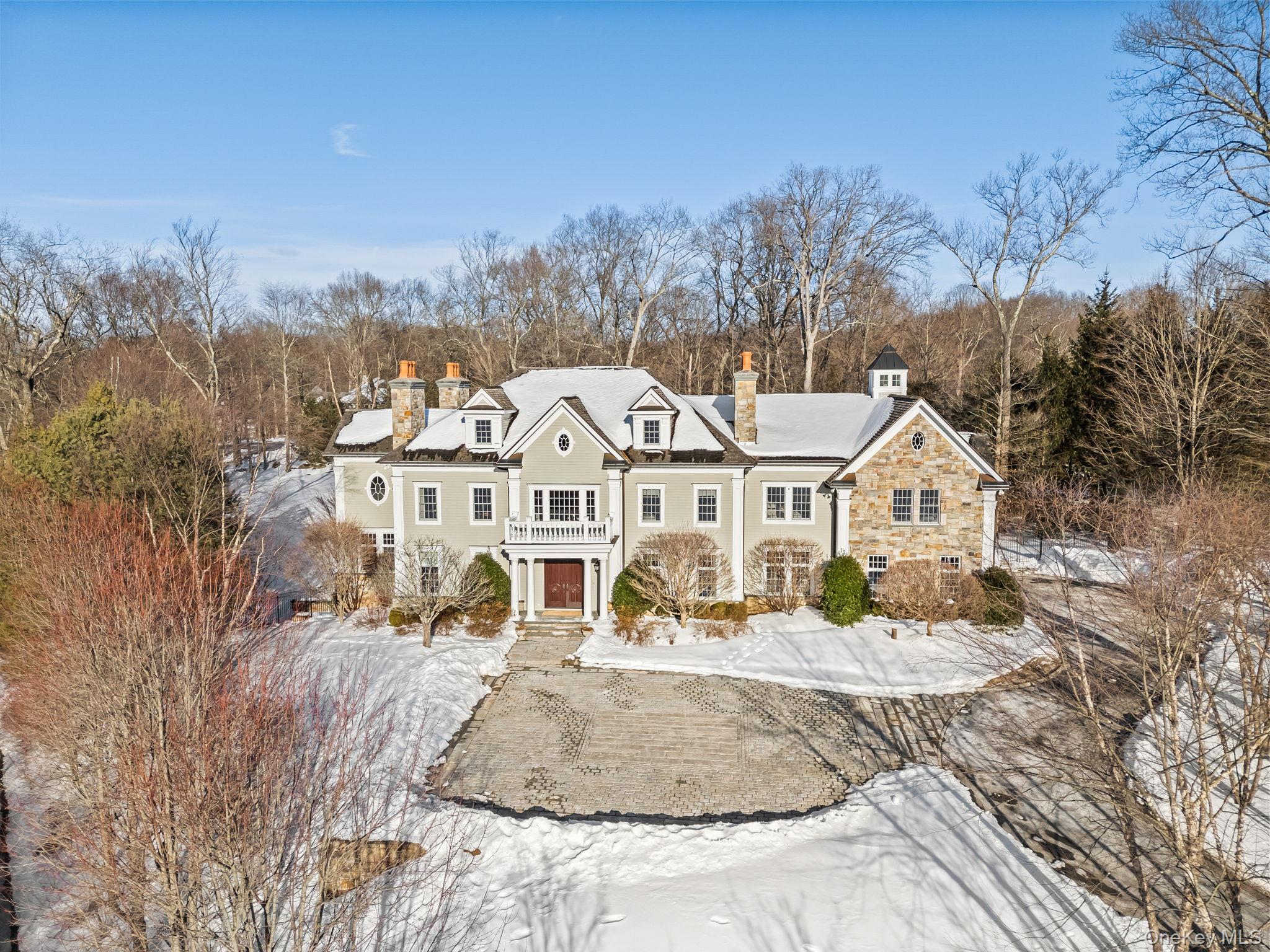Privately set along a winding drive in the coveted Gifford Lake enclave of Armonk, this extraordinary estate offers the feeling of a year-round retreat. Homes of this caliber are defined by extraordinary millwork, full stone cladding, bespoke interior detailing, and museum-quality finishes, reflecting an uncompromising standard of craftsmanship rarely realized in today’s luxury landscape.While rich in architectural pedigree and old-world craftsmanship, the home’s thoughtfully curated color palette, refined designer lighting, and seamless integration of modern materials and fixtures create a sophisticated and current aesthetic. The result is a timeless yet fresh ambiance that feels elegant, vibrant, and thoughtfully modern in its presentation.The exceptional depth of materials and masterful execution throughout this Gifford Lake estate truly distinguish it from anything else on the market. Hand-finished Venetian plaster, intricate custom paneling and wainscoting, richly detailed coffered ceilings, curated designer lighting, premium marble and granite selections, and an extensive stone package that would be extraordinarily costly to replicate today establish a remarkable level of quality.A stone-pillared entry and antique granite courtyard introduce the home’s architectural pedigree. Inside, a dramatic double-height foyer with chevron hardwood flooring, elaborate millwork, coffered ceilings, and a sweeping staircase immediately showcase the craftsmanship carried throughout the residence. Five fireplaces with custom mantels and marble surrounds, crown molding across all levels, bespoke cabinetry, designer wallcoverings, premium marble and leathered granite surfaces, and integrated Sonos audio elevate every space.The chef’s kitchen features Wolf and Sub-Zero appliances, Arabescato marble, a substantial leathered granite island, custom wood cabinetry with glass display uppers, and a glass-wrapped breakfast area filled with natural light.The owner’s retreat serves as a private sanctuary with architectural ceiling detail, a bespoke dressing room with center island, radiant heated spa bath, and refined marble finishes.The fully finished walk-out garden level continues the home’s elevated design with a custom theater and built-in snack bar, brick fireplace lounge, bespoke bar, fitness studio, and resort-style entertaining spaces.Outdoors, full stone cladding, copper detailing, a heated saltwater pool and spa, custom outdoor kitchen, pergola, and professionally landscaped grounds complete this irreplaceable estate offering. Conveniently located near schools, shops, and acclaimed dining in the nearby towns of Armonk, Bedford, and Greenwich, and served by the award-winning Byram Hills School District.   Some Photos enhanced for seasonal representation.