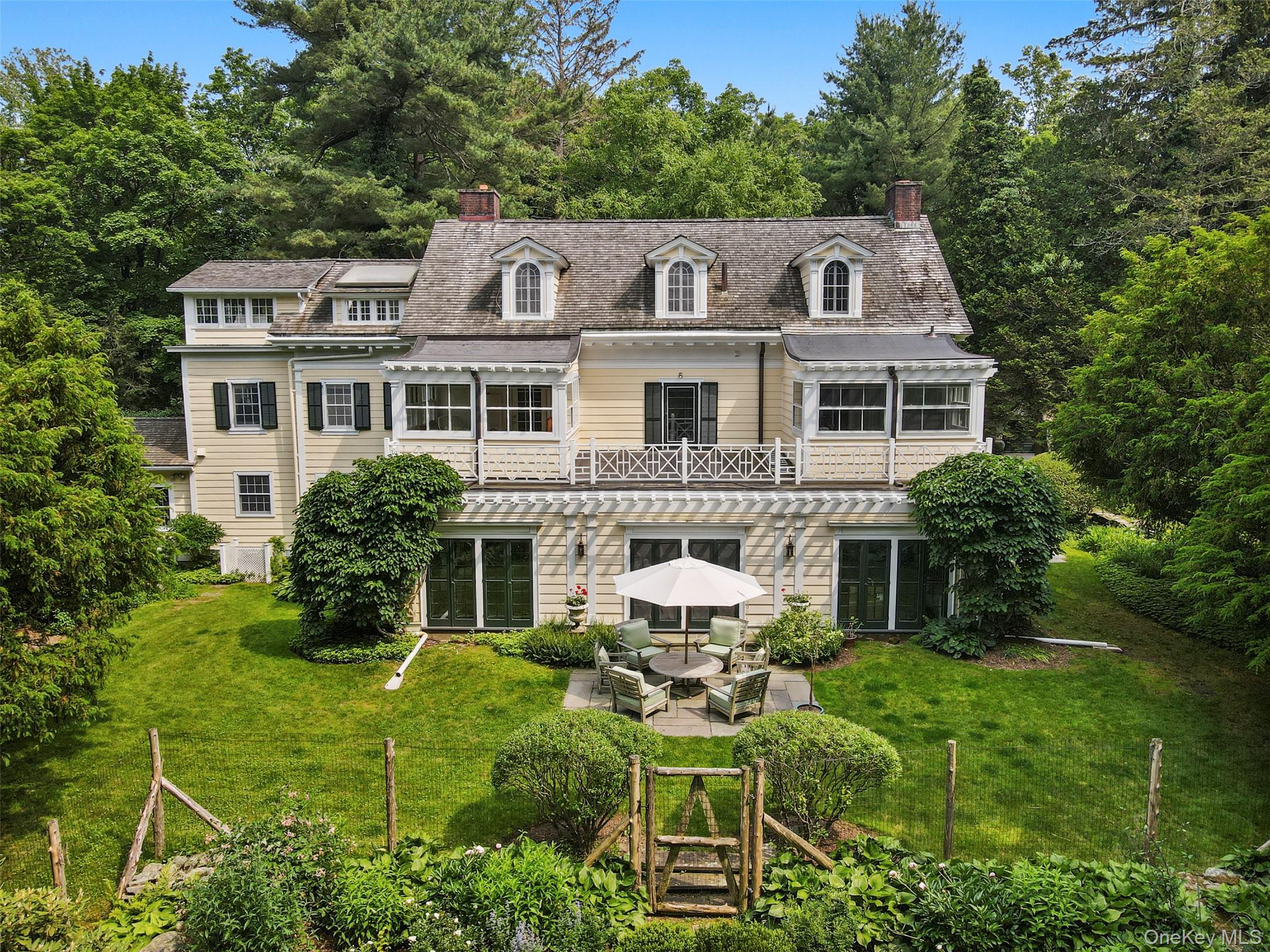 Set back from the road in one of Bedford’s loveliest estate areas, down a tree-lined drive, sits 328 McLain Street. Designed and built in 1906 by the distinguished firm of Delano & Aldrich as the country retreat of Judge Learned Hand, this gracious Colonial residence is nestled on 5.5 acres, with specimen trees, sweeping lawns, and perennial gardens that create a setting of rare serenity. The unmatched privacy and acreage within minutes of trains/schools/shops all just an hour from the city are perfect as a full-time or country house. Its timeless style makes it as appealing now as when it was first built.
The house offers all the hallmarks of Bedford country living: swimming pool and chic cabana, charming guest cottage (think Brooklyn meets Paris), greenhouse, caretaker’s cottage, detached garage, and a maintenance barn.
Inside, the airy sunlit living room and the ample dining room, both with fireplaces, have French doors that open to an open plan sun-filled solarium, creating an easy flow. Outside the sunroom, a bluestone terrace overlooks an English garden that frames the additional acreage beyond. The chef’s kitchen and adjoining sitting room provide a warm, informal gathering space.
Upstairs, the primary suite offers a spacious, tranquil retreat, complete with a fireplace and an ensuite bath. Former sleeping porches have been reimagined as a playroom and guest quarters, while additional bedrooms, each with their own distinctive fireplace, enjoy garden views through large casement windows. The third floor adds further versatility with two generous bedrooms, a classic bath, and a sun-filled skylit artist’s studio with adjoining atelier.
This rare gem truly combines architectural pedigree, gracious proportions, and enduring charm.
More land available