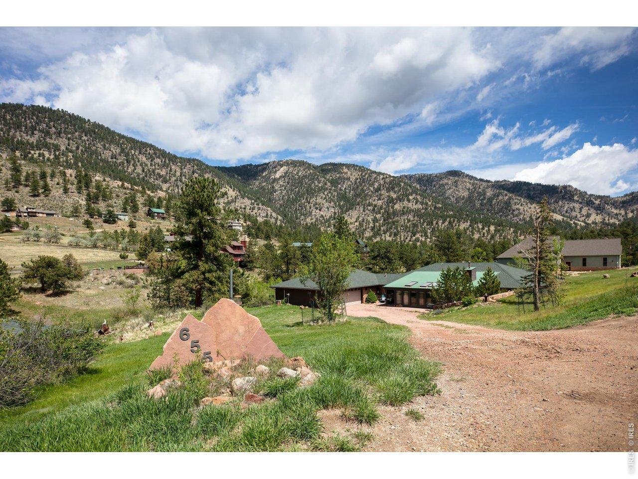 Nestled along the Little Thompson River, this 1.35-acre property in Pinewood Springs offers a front row seat to wildlife and the seasonal river. The 3,000 square foot home includes 3 bedrooms and 3 bathrooms, designed with a comfortable ranch layout and new 4-stage water filtration system. The main living area is a standout, anchored by a wall of windows, warm wood detailing, and a moss rock wall with pellet stove. Natural light carries through the space, with an easy connection to the outdoors. Additional living areas provide flexibility for hosting, working from home, or separate gathering spaces. The kitchen has been refreshed with updated appliances, counters, and opens naturally to the dining and living areas. The primary suite is spacious and private, with a well-executed bath update. New furnace, water heater and A/C. A covered deck and stone patio overlook the Little Thompson, which runs seasonally, bringing movement and sound to the setting throughout the year. The lot offers a mix of open areas and mature trees, creating both usability and serenity. An attached two-car garage PLUS a separate detached garage, well suited for a workshop, studio, or additional storage. A spacious circular driveway makes guest or RV parking a breeze. Kiowa Road is well maintained year-round, providing reliable access, while the home itself is set back to create a quiet, removed feel. Pinewood Springs is a close-in mountain neighborhood just 10 minutes to downtown Lyons, 30 min to Boulder and about 30 minutes to Rocky Mountain National Park. Surrounded by Roosevelt National Forest, the area offers immediate access to hiking, mountain biking, and wildlife viewing, with frequent sightings of deer, migrating elk, and a wide variety of birds. The community also enjoys a private swimming hole and picnic area on the river. The Colorado Cherry Company, a local favorite, is just down the road and a natural place to connect with neighbors over coffee or a slice of pie.