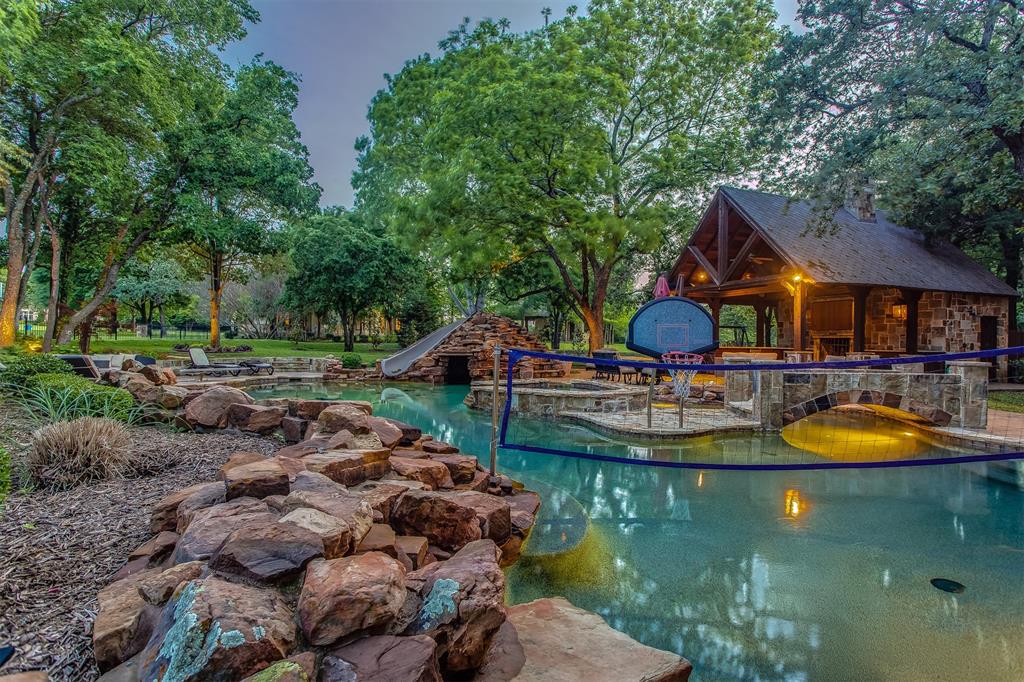 Unmatched beauty in the prestigious guarded and gated golf community of The Estates at Tour 18. This private escape sits on a heavily treed lot and offers a resort style outdoor living area designed for fun and effortless entertaining. The peaceful estate rests on almost two wooded acres and includes a sparkling pool with lazy river, a pool house with shower and half bath, a mosquito misting system, a putting green, fire pit, and a richly appointed outdoor living and kitchen area with bar and sound system. The main house has been exquisitely updated and welcomes you with an impressive entry, vaulted ceilings, designer finishes, and light filled open spaces that will wow your guests. The primary closet is a must see to fully appreciate.  Other features include an oversized driveway for extra parking and basketball, in-ground tornado shelter, full-house generator, roof replaced in 2025, Christmas light ready, and lighting grounding rod.  Many features are smart-home enabled, such as the HVAC system, pool, alarm system, garage doors, entry lock, sprinkler system, and indoor outdoor sound system. Served by award winning Argyle ISD with close proximity to Liberty Christian School and UNT. Ask about special financing when you purchase this property.