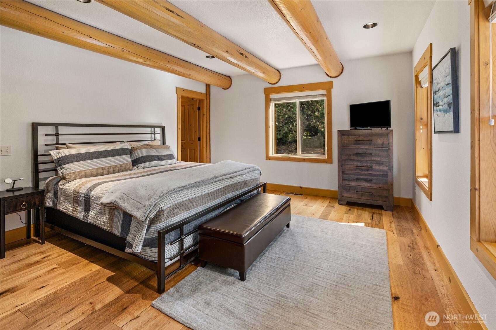Another view of the main-level primary highlights the room’s comfortable layout, natural light, and warm mountain character.
