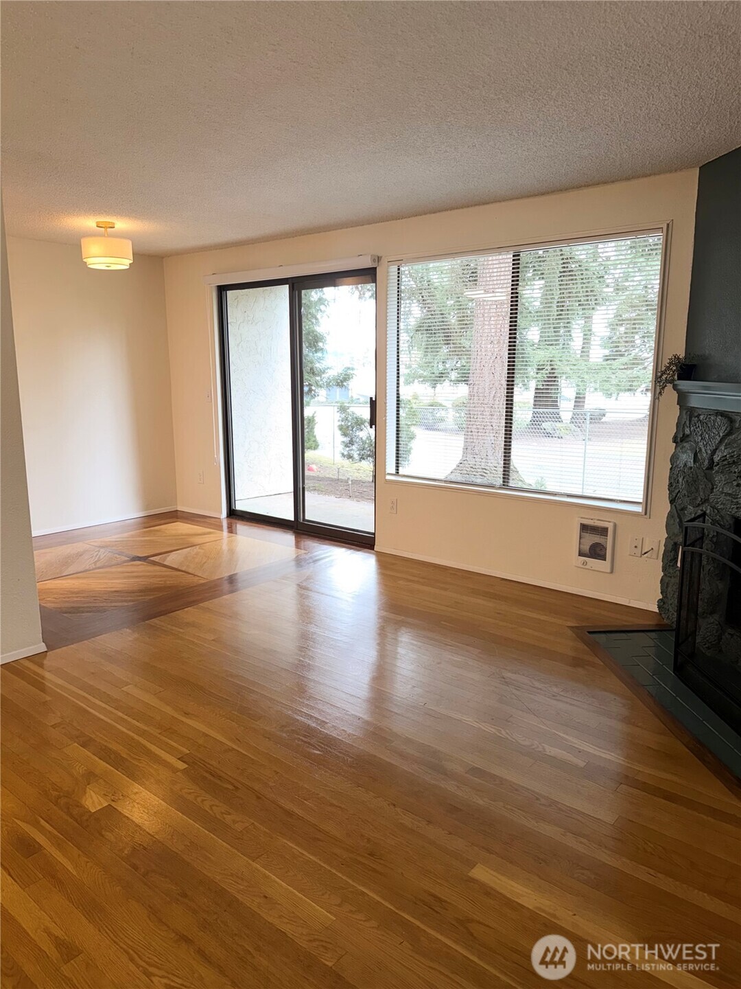 Welcome home to Ridgewood Village Community! This Amazing 1 bedroom, 1 bathroom condo in Kirkland just became available for sale! This ground-floor end unit offers comfort and convenience, just minutes from I-405, Totem Lake, Downtown Kirkland, Juanita Beach, Microsoft, and Google. Enjoy an updated kitchen with stainless steel appliances and a refreshed bathroom. Hardwood flooring flows throughout the main living areas, leading into a cozy living room featuring a beautiful wood burning fireplace. The spacious bedroom features soft Berber carpet for added comfort and storage shelving in the closet. The kitchen leads to the beautiful dining area that opens to your patio, perfect for relaxing. Additional features include in-unit washer and dryer, covered parking with one assigned covered space and plenty of guest parking. The patio also includes an outdoor storage. Water, garbage, and sewer are included in the HOA monthly dues. This home is a GREAT investment Property if you are looking for one! or A Great Home to unwind after a long day!