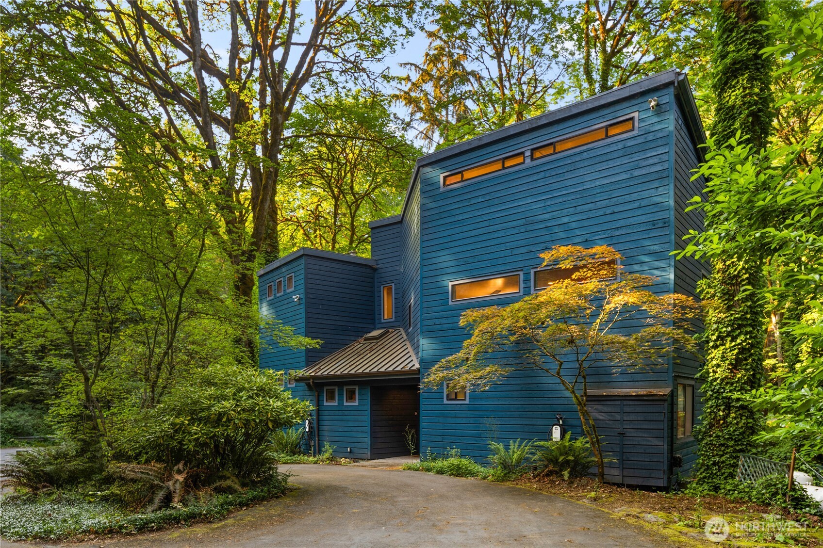 This NW Contemporary home offers a serene, nature-filled setting with views of a winding creek and no visible neighbors. Private Mercer Island treehouse sanctuary is waiting! Architecturally striking, this home features a new roof, carpet, paint, windows, and electrical, along with a fully remodeled kitchen, soaring ceilings, two electrical charging stations, and expansive windows that bring the outdoors in. Open-concept family and dining areas. A warm, wood staircase leads to the spacious primary suite, complete with a lofted workout area and a luxurious bath. The ground level includes a living room, office, and two additional bedrooms. Peaceful atmosphere with private trails, & easy access to shopping center.
