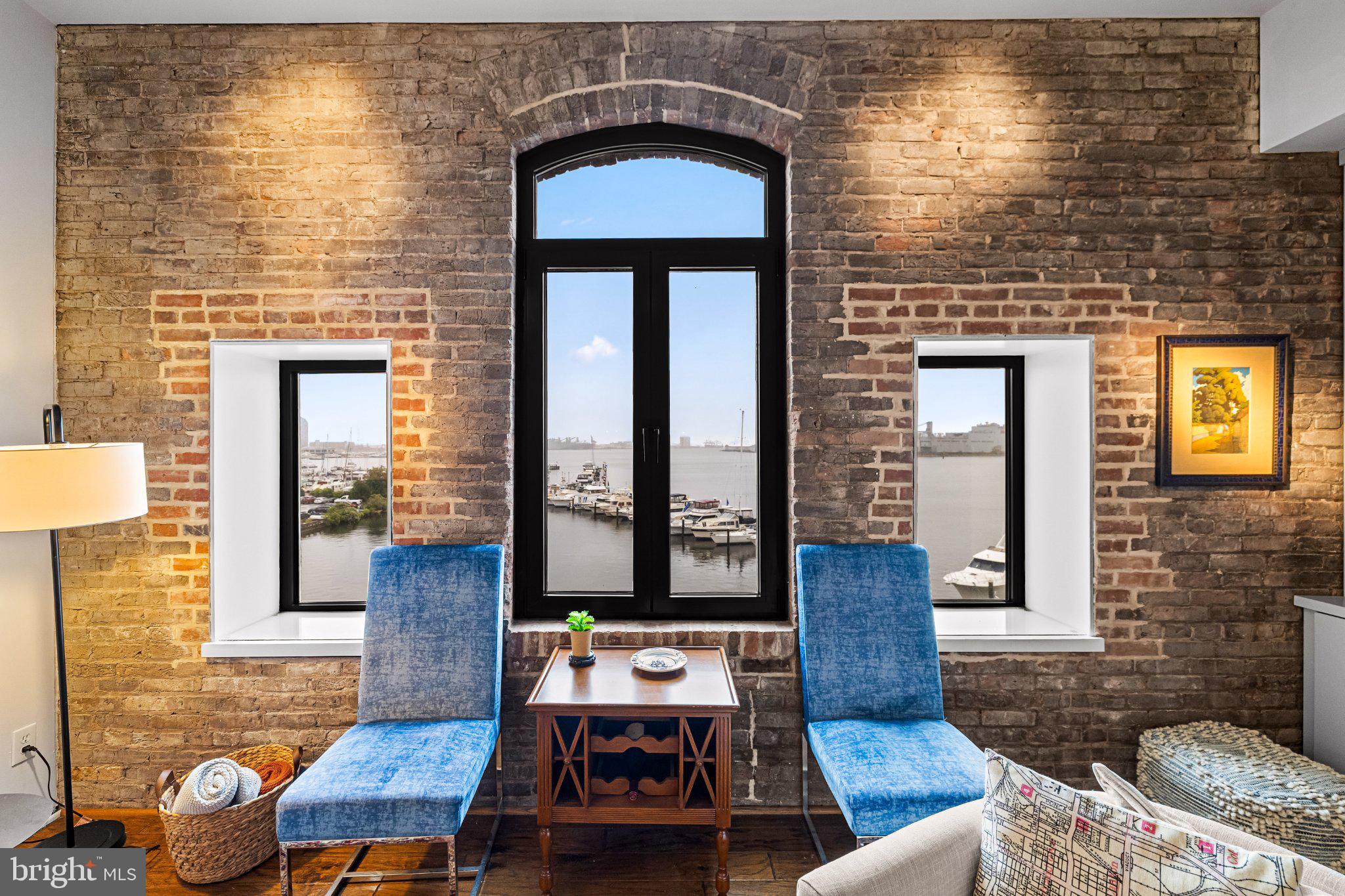 Enjoy exceptional waterfront living in this beautifully appointed one-level, two-bedroom, two-bath condominium at historic Henderson’s Wharf in the heart of Fells Point. With direct Inner Harbor views, this distinctive residence combines historic charm with sophisticated modern updates. Rich hardwood floors and exposed brick walls reflect the character of the building, while the updated gourmet kitchen features stainless steel appliances and ample cabinetry. The spacious owner’s suite offers an abundance of storage with two generous closets featuring custom built-in shelving, while additional closets throughout the home provide exceptional storage rarely found in city living. Two deeded parking spaces in the covered garage add safety and convenience. Henderson’s Wharf offers a secure, concierge-served environment with a welcoming elegant lobby, private gym, charming courtyard seating, and a private event space. Set along a picturesque cobblestone street in historic Fells Point, the residence places waterfront dining, shops, entertainment, and the vibrant energy of the neighborhood just outside your door—all while offering the comfort, privacy, and security of a premier waterfront community.