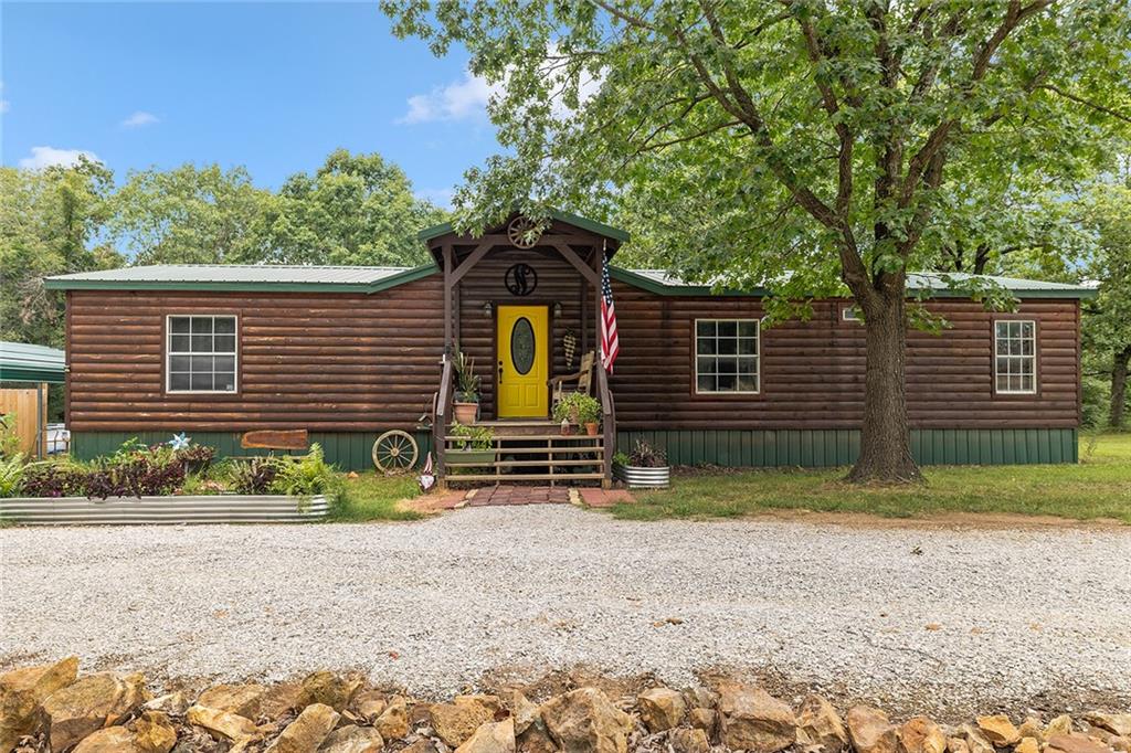Welcome to your own private retreat on 20 beautiful acres! This log-sided manufactured home is nestled among rolling hills and mature timber. The land is mostly wooded, with a seasonal creek that runs at the bottom of the first hill — flowing during heavy rains. The property is partially fenced with barb wire along the sides and back. Step inside to find 3 spacious bedrooms and 2 full bathrooms. A formal living room greets you at the front of the home, leading into an open-concept kitchen and cozy family room. Home has newer vinyl plank tile. The pellet stove adds warmth and charm while helping reduce propane costs during the colder months. There is a central all-in-one electric heating and cooling system as well.. The home also features a durable metal roof for long-term peace of mind. Enjoy the outdoors from the large back deck, part of which is enclosed and currently used as a small workshop. Additional features include a 30-amp RV hookup, a second septic system near the campsite area, and a blue connex container with its own 200-amp electrical service—perfect for storage or future expansion. Whether you're looking for a full-time residence, weekend getaway, or hunting basecamp, this property has endless potential.