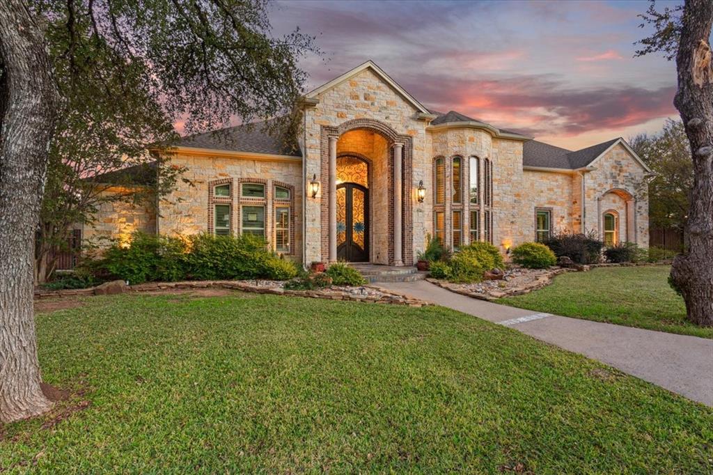 Welcome to 10020 Hidden Bluff, an exceptional estate tucked away in the prestigious Hidden Valley community. Offered at under $200 per square foot, this remarkable property presents an increasingly rare combination of scale, luxury, and value. Situated on a generous .710-acre lot, the residence offers 7,677 square feet of thoughtfully designed living space, blending refined finishes with everyday comfort. With five bedrooms, four and a half baths, and a five-car garage—including an oversized bay ideal for an RV or boat—the home was designed for both grand living and practical needs. Expansive living, kitchen, and dining spaces flow seamlessly into a heated, cooled, fully enclosed extended living patio with a fireplace and an additional kitchen, creating an incredible setting for year-round entertaining. The gourmet kitchen is a showpiece, with custom cabinetry, a six-burner gas range, double ovens, warming drawer, oversized refrigerator, and both breakfast and formal dining areas. The first-floor primary suite offers a private sitting area, spa-like bath, and expansive closet, plus a secure safe room. Entertainment options abound, including a dedicated theater room with surround sound, theater seating, and a full kitchen—perfect for movie nights or hosting a crowd. Upstairs, an additional private suite with its own bath and a second laundry room provides added flexibility and convenience. Outside, the backyard becomes a private retreat centered around a spectacular pool with a remote-controlled waterfall. A screened-in pool house with a half bath completes the outdoor living experience, creating an inviting space for relaxing and entertaining in all seasons. This home offers a compelling opportunity to own more than 7,600 square feet in one of the area’s most desirable communities. A rare offering where luxury, lifestyle, and value come together beautifully. Zoned to South Bosque Elementary, River Valley Middle School, and Midway High School.