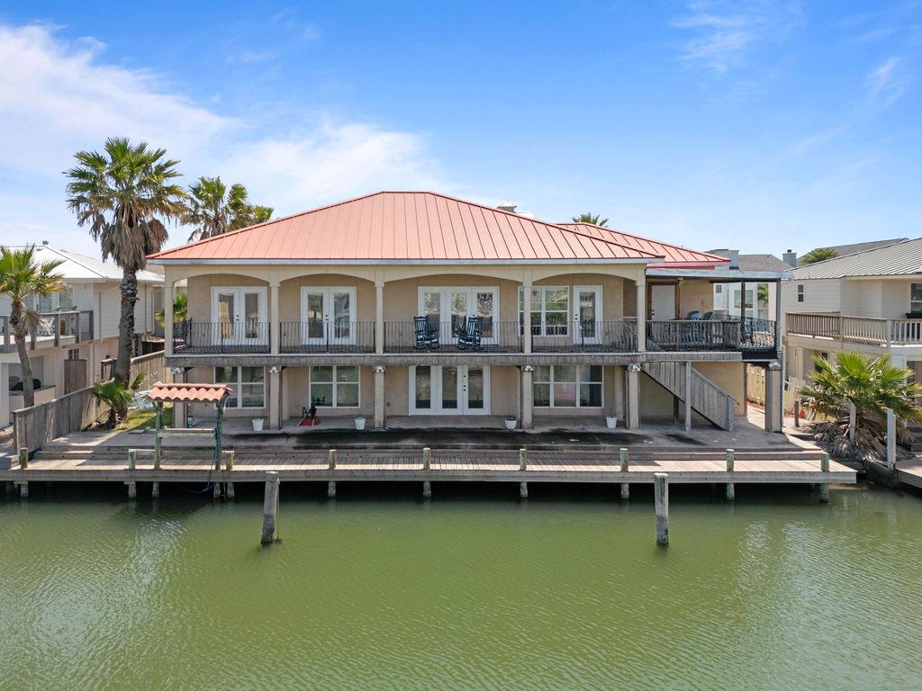 Open and spacious Mediterranean-style home in coveted Key Allegro! This stunning 5-bed, 5 bath, 4,343 sq. ft. waterfront retreat offers multiple indoor and outdoor living spaces. The first floor features a tiled living area, three bedrooms with en-suite baths, a second kitchen, and French doors leading to a covered patio. Take the stairs or elevator to the main level, where you'll find wood floors, a spacious living area, the primary suite, a 4th bedroom suite, and an open kitchen and dining area. French doors lead to a covered deck and separate entertaining deck, perfect for enjoying coastal breezes. The home boasts a circle drive, stucco exterior, metal roof, new fish cleaning stand, and a boat dock with ample space for a boat lift. A true waterfront gem—don't miss this Key Allegro beauty!