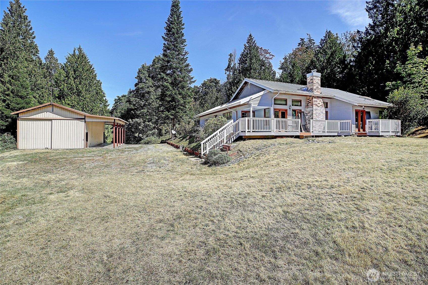 Opportunity knocks in the Camano Country Club—no HOA & optional beach access! This 2BR + DEN, 2BA home is perfectly situated on 5 private acres with a HUGE SHOP!  2,369 sq. ft. of living space w fantastic floor plan.  Formal entry opens to spacious den, vaulted living rm w cozy propane stove, formal dining rm & large kitchen w island & eating nook. Main floor with hardwoods & ready for your flooring finishes. Primary bdrm w en suite & WIC. Propane fireplaces on both levels, metal roof. Needs TLC—ideal for renovation loan or sweat equity. Oversized 2-car garage, 3-bed septic, and Camano Water Association. Quiet setting just minutes from beaches, parks, and schools—no ferry required!