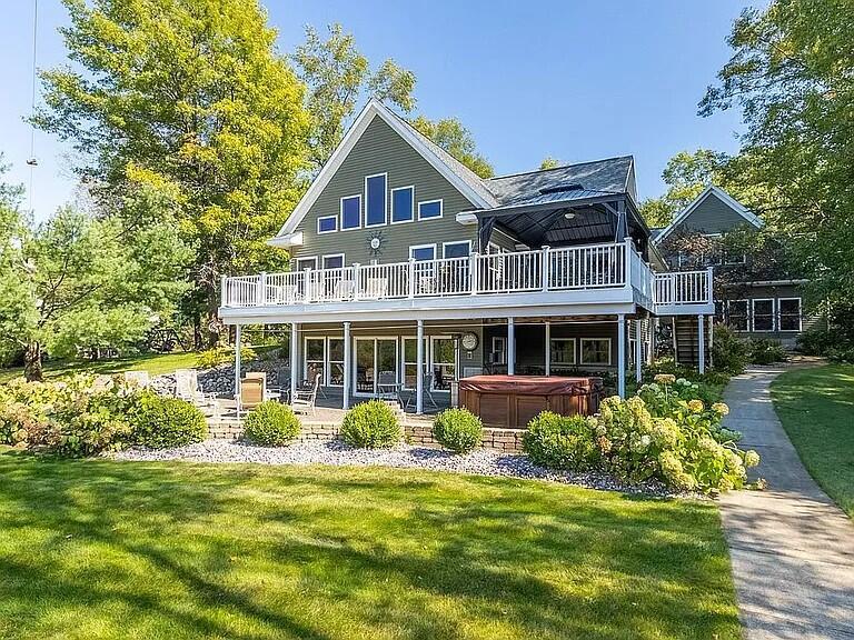 Your lakeside dream home is here! Tucked away on 2 private, wooded acres along the shores of all-sports Long Lake, this 3,832-square-foot custom-built retreat offers the perfect balance of high-end comfort, thoughtful design, and unmatched lakefront lifestyle. Step into the heart of the home, a stunning open-concept kitchen, living room, and dining area with soaring vaulted ceilings and expansive views of the lake. Designed with the entertainer in mind, the chef's kitchen features a massive custom island with storage on all four sides, a built-in sink, and seating for five. Elegant granite countertops are paired with dual dishwashers, dual ovens, a microwave/convection oven, and two built-in pull-out trash/recycle bins. Plus, two garbage disposals make clean-up a breeze. Every detail is carefully crafted for function and flow.The spacious living room centers around a stacked-stone gas fireplace that not only adds cozy ambiance but is also connected to the home's thermostat, activating as a backup heat source when needed. Floor-to-ceiling windows and sliding glass doors open to a heat-resistant composite deck, creating seamless indoor-outdoor living with panoramic water views and attached Gazebo. The main-floor primary suite is a luxurious escape, featuring a vaulted ceiling, large walk-in closet, jet tub Jacuzzi, dual vanities, and a glass-enclosed walk-in shower. Upstairs, a lofted living space overlooks the lake and living room, leading to a large bedroom and full bath. The 1,362-square-foot walk-out lower level is built for entertainment and extended stays. It includes a recreation space with 2 additional bedrooms, an office, and 9-foot ceilings with full-height windows overlooking a bricked patio. The lower-level laundry room provides added storage and convenience. Additional home features include two water heaters to ensure ample hot water for large groups and gatherings. The oversized 3-car garage boasts 11-foot ceilings, large 9'x18' doors, and a finished third bay that functions as a multipurpose entertai