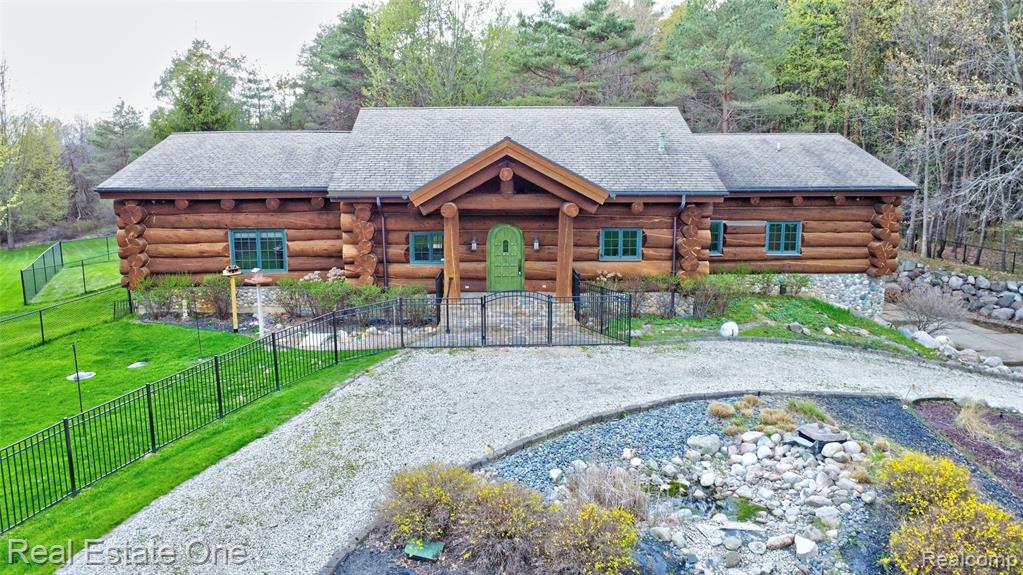 Custom-built log ranch home with over 3,700 sq ft set behind a gated entrance on 20 private acres. Constructed in the 2000s using logs imported from New Mexico, this home showcases true craftsmanship, scale, and materials that are rarely found today. The main living area is anchored by a dramatic floor-to-ceiling stone fireplace and framed by massive beams and warm natural wood throughout. The layout was recently opened up, creating a seamless flow between the kitchen, entry, and great room. The kitchen blends rustic architecture with high-end function, featuring generous prep space, quality appliances, and a large island that connects naturally to the heart of the home. This ranch layout includes 3 bedrooms and 2.1 baths, highlighted by a spacious primary suite designed to feel private and separate. A sunroom just off the main living area leads to an expansive deck overlooking the property. The finished lower level provides additional living space, extensive storage, and two separate wine cellar areas. Outdoors, the setting speaks for itself. Deer are frequent visitors to the front of the property, adding to the peaceful, estate-like feel. The land also includes a charming chicken coop and a large pole barn that has been recently insulated and equipped with heat for year-round use. Additional major features include a slate roof with an approximately 100-year lifespan and a whole-house generator. A rare combination of land, privacy, and architectural presence — designed for those who appreciate quality, space, and a true connection to the outdoors.
