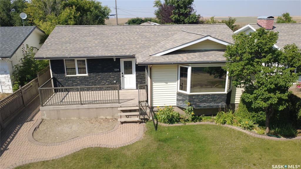 If you’ve been thinking about making a move to a community where kids can still walk to school, families know each other, and Friday night might mean skating or curling instead of fighting traffic, this one deserves a look. Located just a short walk from Herbert’s K to 12 school and the rinks that become the winter heartbeat of the community, this spacious 1298 sq. ft. home at 528 Annable Street has the room a growing family needs. The gorgeous kitchen is a standout with stainless steel appliances, loads of cupboard space and a powered island that gives everyone a place to gather. The dining room is easily large enough for the whole crew, with garden doors leading to a family-sized deck and fully fenced backyard. The enormous living room is flooded with natural light from the bay window, while the separate front entry deserves its own applause because there’s actually room for everyone to come home at once without the traditional doorway traffic jam. The main floor also offers a secondary bedroom, 4-piece bathroom, spacious primary bedroom and 2-piece ensuite. Then there’s the basement, which is practically another house. A generous rec room gives you plenty of space for family playtime or movie nights, along with 3 large bedrooms, an office, and storage galore. The double detached garage had its own glow-up in 2018 with a new heater, new doors and fresh shingles. Other major updates include a 2024 high-efficiency furnace, 2023 on-demand water heater with circulation pump for quick hot water, and new vinyl plank flooring in the primary bedroom and ensuite in 2022. But the crown jewel? Four additional lots across the back alley, adding 24,000 sq. ft. of bonus property. Park the extra vehicles and toys, build yourself a skating rink, or do what the current owners have done and create one fantastic garden. If you’re looking for more space, more freedom and a place where you and your kids can actually be part of the community, Herbert might just be calling your name.