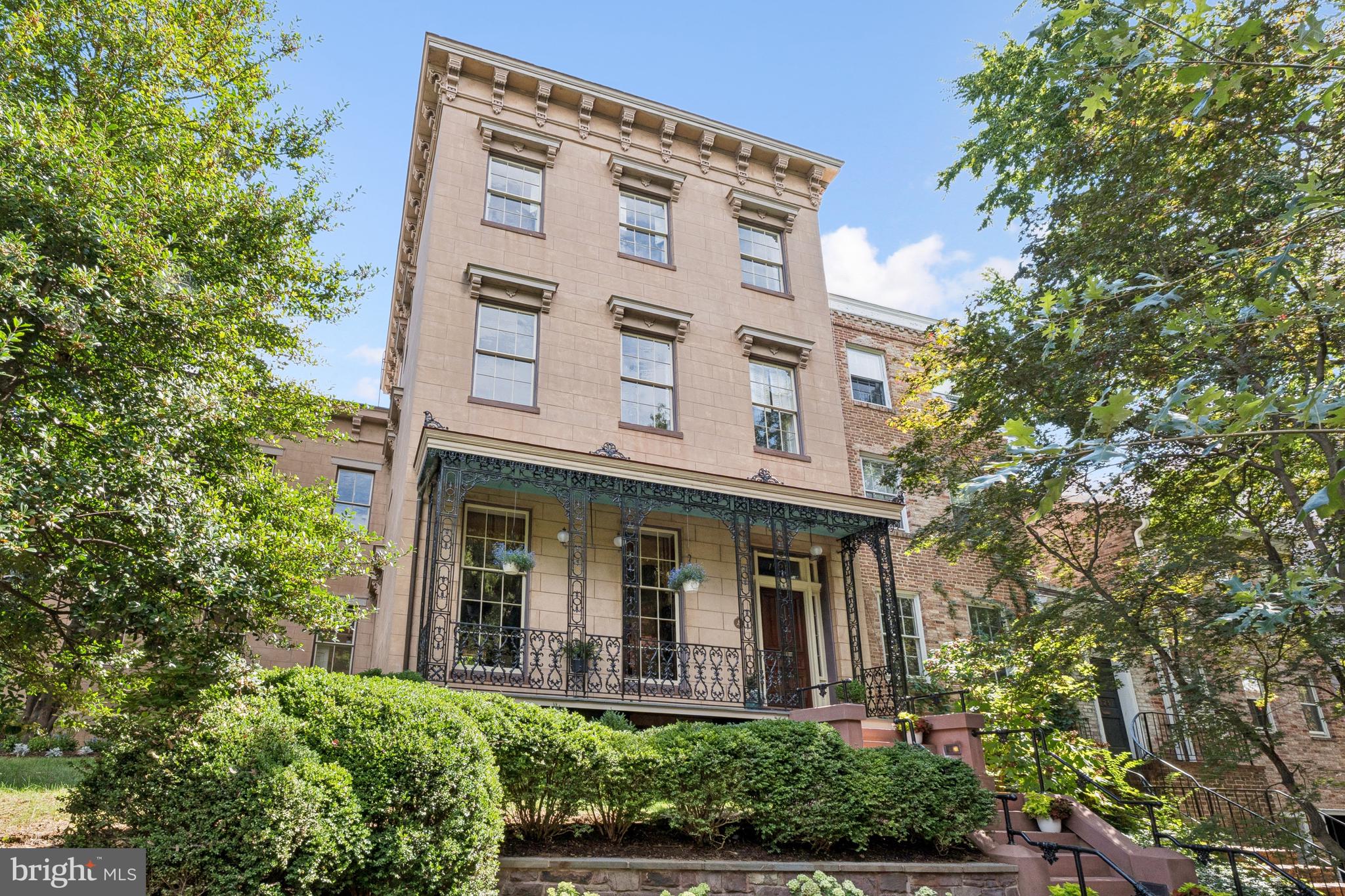 The Alexander Graham Bell House | Step into a Gilded Age fantasy with this extraordinary Greek Revival corner residence, built in 1854 and once home to Alexander Graham Bell and his family. Steeped in history and architectural splendor, this six-bedroom, six full and two half-bath Georgetown estate is a masterwork of 19th-century elegance, meticulously preserved and thoughtfully updated.A Grand Historic InteriorSpanning four gracious levels, the home is centered around a sweeping mahogany staircase rising beneath a stained-glass skylight. Echoes of Upstairs/Downstairs living abound—from working call bells connecting principal rooms to the kitchen, to grapevine and acanthus-leaf moldings, faux bois doors, paneled window shutters, and intricate brass hardware.The twin parlors—perfect for formal entertaining—feature marble fireplaces with carved acorn details, gilded crown moldings and chandelier medallions. Stained-glass pocket doors lead into the formal dining room, where striped wood floors extend into a ballroom-like space framed by Palladian triple-hung windows that open to the terrace garden and fountain. Period chandeliers, cut-crystal sconces, and etched glass fixtures complete the unified decorative scheme.  The main level half-bath features an antique Edward Johns & Co sink, period high-tank commode, and opaline glass light fixtures.Chef’s Kitchen & Terraced GardenThe light-filled, eat-in kitchen blends historic charm with modern functionality. Anchored by a wood-burning fireplace, it includes Wolf and Sub-Zero appliances, a mix of butcher block and stone counters, and fully functional original call bells. French doors open directly to the lush, walled terrace garden—an urban sanctuary complete with mature plantings and a stone fountain.Private Quarters & Lavish SuitesThe original second-floor primary bedroom is bathed in natural light and adjoins a marble-and-tile ensuite bath with Waterworks fixtures and a towel warmer. A nearby study/library features a marble fireplace and access to a canopied terrace, as well as a concealed Eastlake-style wet bar outfitted with a copper sink, pomegranate-motif painted tiles, and herringbone cabinetry.A later addition brings a private octagonal primary suite enhanced with opaline glass tiebacks, floral plaster medallion, and dual bathrooms. One features a marble sink, tile shower, and Waterworks fittings; the other offers a large marble vanity within a spacious dressing room, complete with a built-in ironing station and Jacuzzi tub.On the third floor, two additional bedrooms each offer marble fireplaces, custom built-ins, and full ensuite baths with clawfoot tubs, pedestal sinks, and antique light fixtures.Lower LevelAccessible via private staircases, the fully equipped lower level includes a two-bedroom in-law or rental suite with twin closets, a full and half bath, and a dedicated laundry. Period elements abound: original tile floors, a Dutch door, cast-iron hardware, and tongue-and-groove detailing. The historic butler’s pantry and second laundry station add charm and functionality.Additional Features Include:Oversized two-car garage with ample storage and recent improvementsCopper flashing and drainage throughoutOriginal enamel doorknobs, locks, and fixtures throughoutMultiple fireplaces, including wood-burning and decorative marbleThoughtful updates with Waterworks, Lefroy Brooks, and Czech & Speake fixturesA Rare OpportunityLocated within the Georgetown Historic District and listed on the D.C. Inventory of Historic Sites, the Alexander Melville Bell House represents an extraordinary convergence of heritage, craftsmanship, and luxury. It is not merely a home—it is a legacy, ready for its next steward.