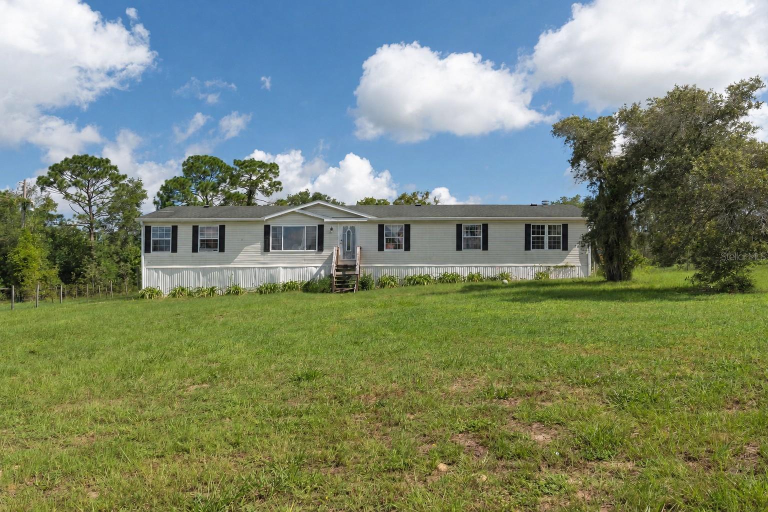 Virtually Staged. What if the opportunity isn’t just the home but the land, the space, and what you could create with it? Set on 2.5 fully fenced acres in Brooksville, this 2006 manufactured home offers approximately 2,310 square feet with 4 bedrooms, 2 bathrooms, multiple living areas, and plenty of room both inside and out. Add in a detached storage shed, mature trees, and 2.5 acres to work with, and there is plenty here for someone with a little imagination who can see what this property could become. The home is being sold AS-IS and does need TLC, repairs, and updating, but for the buyer who can see beyond its current condition, this is an opportunity to take an existing home with generous square footage and make it your own. Have you considered a rehabilitation loan? For buyers interested in purchasing a home that needs improvements, rehabilitation financing may provide an option to finance the purchase along with certain renovations. Ask about lenders who can explain how rehabilitation financing works and help determine eligibility. If acreage, space, and the opportunity to make a property your own are on your wish list, this one deserves a closer look. Schedule your private showing and come see the possibilities for yourself. Some photos have been digitally edited to remove personal belongings and clutter. Schedule your private showing today and see firsthand the space, acreage, and possibilities this property has to offer.