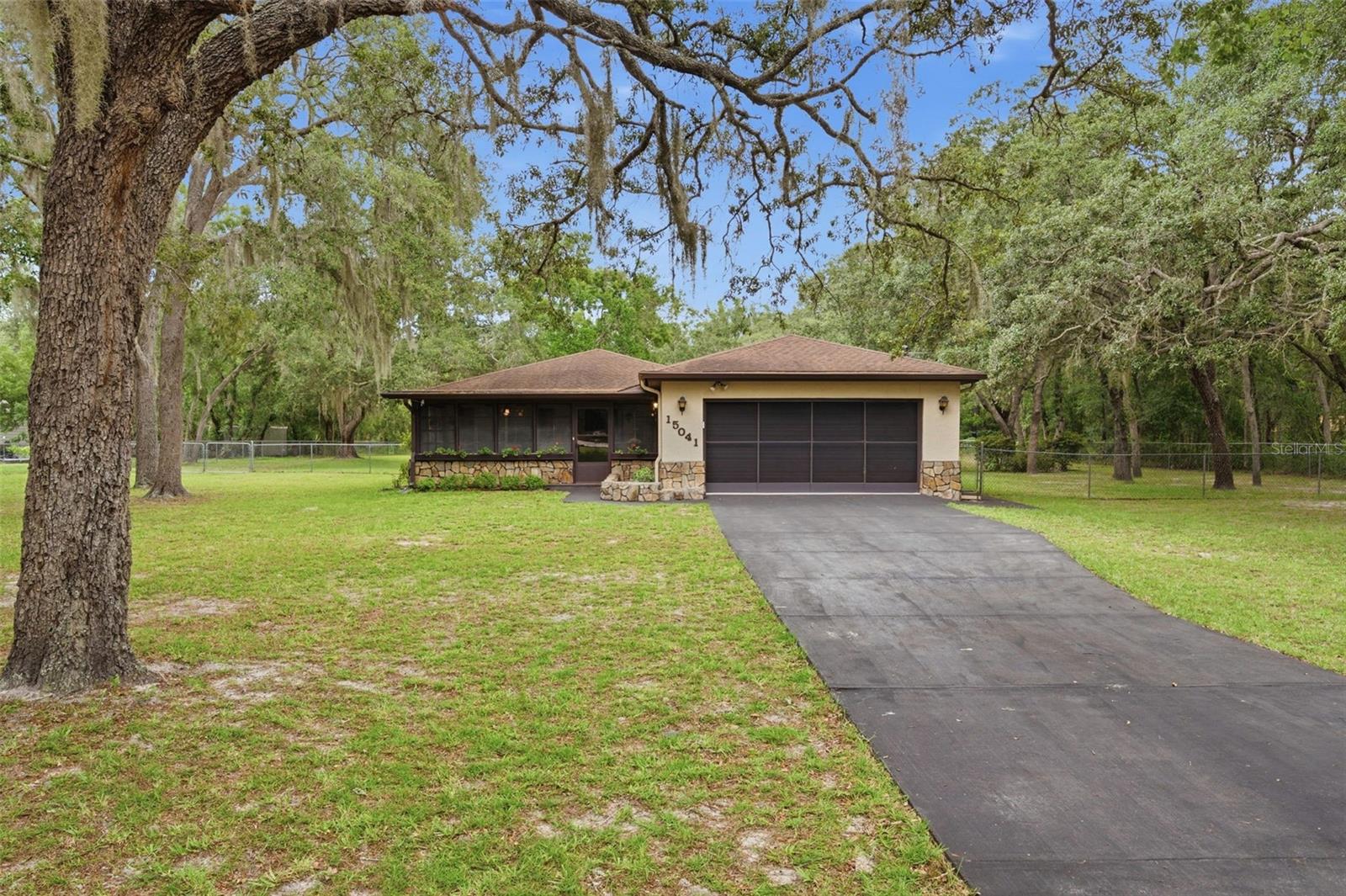 Virtually Staged. WELCOME TO YOUR COUNTRY RETREAT at 15041 Camrose Ave, Spring Hill, FL in Pasco County. Your MARVELOUS home features 3 bedrooms + office, 2 bathrooms, 2 car garage with nearly 4,300 total sqft on 1.2 acres or 150' by 334' of HIGH & DRY cleared land with NO HOA, NO CDD & NO FLOOD ZONE. This AMAZING property features the main 3/2/2 block house with the attached garage, a detached BARN/GARAGE with additional covered parking for 4+ vehicles and a SEPARATE IN-LAW SUITE/APARTMENT with a GIGANTIC storage room totaling 992 sqft located above the barn/garage. Though the studio apartment (kitchenette, bedroom, combined living/dining areas, full bath with shower) needs work, it has 992 sqft of space to create your DREAM STUDIO! There is PLENTY of parking for multiple vehicles on the long asphalt driveway. Stepping inside the covered & screen front porch, you'll LOVE the WIDE OPEN FLOOR PLAN consisting of the foyer, kitchen, living & dining rooms. The living room features REDWOOD walls & PHENOMENAL wood beams on the ceiling. There is a SUPER COOL REDWOOD DUTCH DOOR that leads to the garage. Create family memories in the dining room featuring a ceiling fan with Tiffany-style stained glass light, cabin-theme wood panels & built-in corner shelf. The UPDATED kitchen consists of PREMIUM wood cabinets, Corian counters, tile backsplash, pantry closet & deep double stainless steel sink overlooking a window. The primary bedroom can easily fit king-size furniture & has a fan, chair rail, DUAL closets & private bath. The primary bathroom has tile floors, cultured marble sink with rose design, vanity storage, medicine cabinet, pendant lights & private toilet & sunken step-in shower with green speckled tile. Bedrooms 2 & 3 are virtually equal in size to each other & feature ceiling fans & built-in closets. There is a LARGE office which is currently utilized as the quilt room. This quilt room, EASILY a 4th bedroom, features etched glass bifold doors, ceiling fan & track lighting. The 2nd bathroom consists of ceramic tile floors, cultured marble sink, tub/shower combo, storage vanity, medicine cabinet & linen closet in the hall. Access the backyard to the covered concrete patio through the double glass sliding doors off the living room. Run a business from home or need space to tinker? NO PROBLEM! In addition to the barn/detached garage, there is a shed (approximate dimensions 18'x10.5') & another covered storage area behind the barn (approximate dimensions 30.5'x8'). The RV carport does not convey but it is negotiable. Majestic OAK TREES reside on the property & provide shade & enjoyment within the fenced area PERFECT for your furry or feathered friends like dogs, cats, goats, ducks & chickens. This property is serviced by private well & septic. House systems: AC (manufacture date 2/2020), Roof (4/2011). MORE great things to LOVE about this home include: built-in picnic table & seating by the barn, REPURPOSED "Augusta Block" bricks from old brick roads in St. Pete pave the picnic area, granite stone exterior accents, quarry tile & coffered-design ceiling at the front porch, gutters, newer garage door with screens & a garage with American diner retro vibes will have you craving a burger, fries & milkshake. This home was BUILT & LOVED by the current owner! BLOCK HOUSES on ACREAGE are in demand! The location is SUPERB near restaurants, shopping, schools, places of worship, medical plazas, beaches & tourist attractions. MAKE THIS YOUR FUTURE HOME!