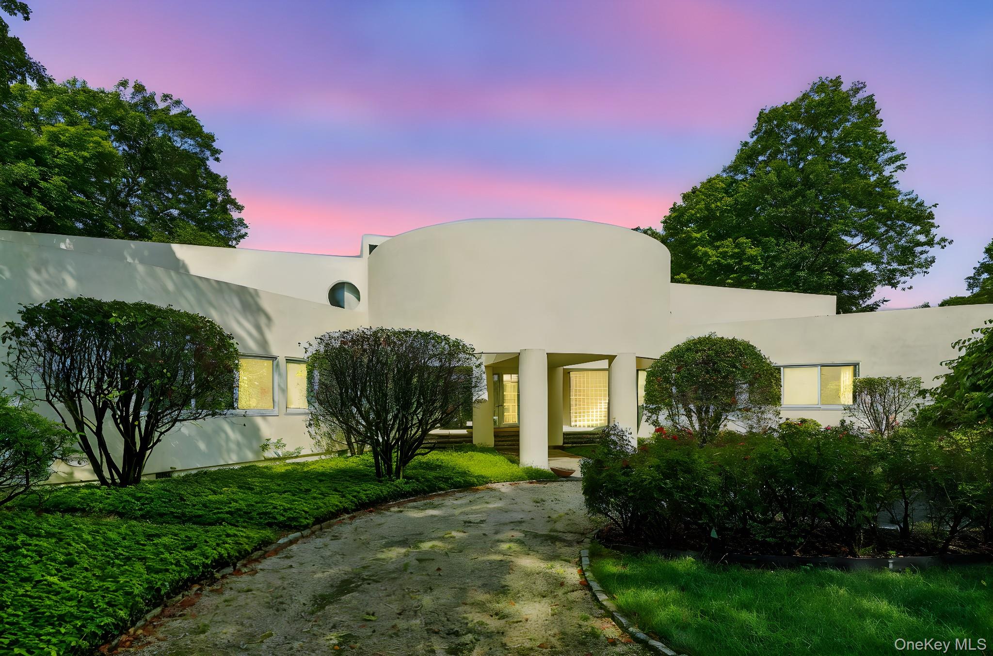 Nestled in breathtaking natural surroundings, this modern architectural masterpiece by renowned designer Myron Goldfinger offers three levels of striking contemporary design. The residence features a soaring three-story curved ceiling, a dramatic floating staircase, and expansive open-plan living and entertaining spaces that frame the home’s private setting. The main-level primary suite provides a serene retreat, while the sleek, state-of-the-art kitchen is ideal for both everyday living and entertaining. Additional highlights include a fitness room, Shoreline pool with cabana, and a private tennis court. A 4+ car attached garage and below-ground oil heating add convenience. Located just 45 minutes from New York City, this one-of-a-kind residence blends luxury, privacy, and timeless modern design.