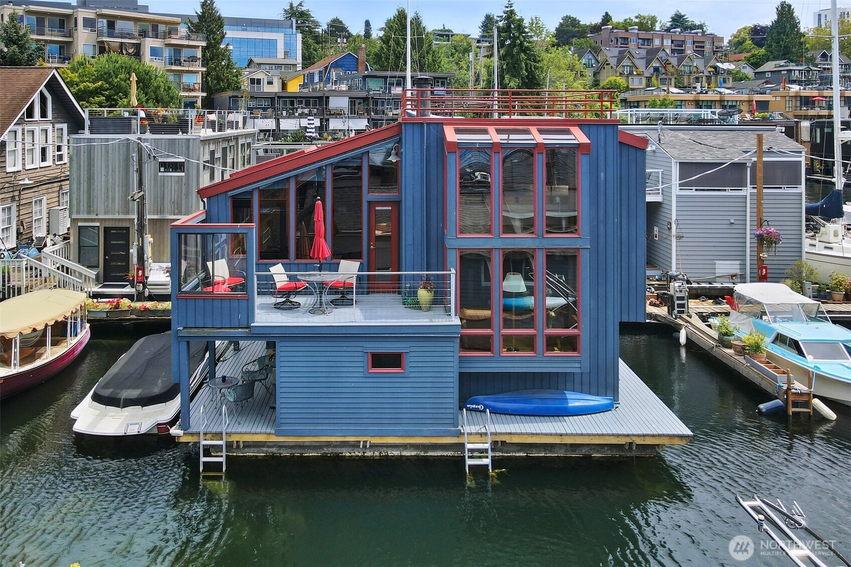 Renowned floating home American Institute of Architects James Jessup designed this floating home in 1975 for a local Seattle couple who were avid boat racing buffs. They kept a 24’ sailboat moored next to the home and could take off on a minute’s notice.  True to form, this Jessup home showcases multileveled spiraling spaces from the study to the living room, on up to the primary bedroom.  A creative retractable ladder provides access to the most magnificent views on the roof top.  The cathedral windows expand throughout the 1,200 square foot home, alluding to a much larger interior.  The smell of cedar wraps your senses and a woodsy spirit with an economy of space rings true. Designed with nature in mind, this home has the perfect backdrop of sailboats, Space Needle views, and the slight sound of water gently lapping. Own a piece of Seattle’s history while living amongst a community of fellow floating home enthusiasts.