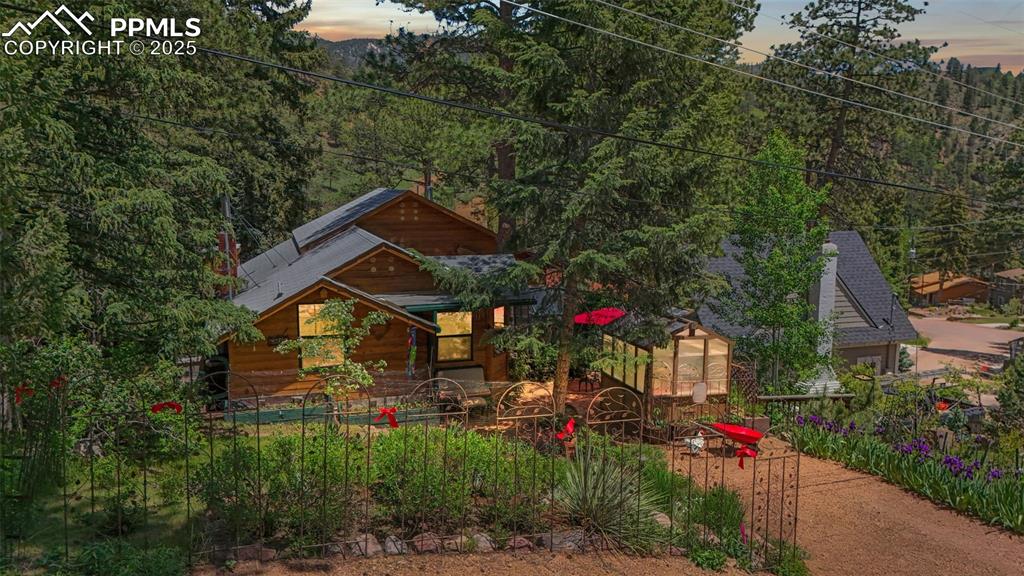 Welcome to a meticulously maintained 3-bed, 3-bath mountain retreat in the heart of Green Mountain Falls. Perched above the lake with views of the iconic town gazebo, this warm and inviting cabin blends rustic charm with modern upgrades in all the right places. Step inside to find recently restored and expanded wood flooring, fresh interior paint, and a cozy living room featuring the home’s original wood-burning fireplace—now updated with a cast iron insert and fan for extra efficiency. The primary suite offers a serene garden and lake view with sightlines to the ridgeline beyond. It also includes a private flex space—perfect as a pocket office, library, or creative nook—complete with a skylight, and a built-in bookshelf. Downstairs, the walk-out garden-level bedroom has its own bathroom and a 220-volt outlet, offering potential to create a separate living unit with a kitchenette. Outdoor living shines here, with two greenhouses, lush established perennial gardens, and a fully insulated, wired cottage with radiant heater and ceiling fan—ideal as a guest space, art studio, or home office. This home is equipped with thoughtful features throughout, including a HEPA air filtration system with Wi-Fi monitoring, a high-efficiency furnace, a 100-gallon water heater, and closed-cell spray-foam insulation in the crawlspace for increased energy efficiency (saving up to 20% on winter heating). A 220-volt outlet is ready for electric vehicle charging or RV power, and the gas grill is connected to a permanent gas line for effortless outdoor cooking. Additional highlights include Leaf Guard gutters, a Jacuzzi tub surrounded by a custom stone mosaic in the guest bath, and a striking stained glass mosaic window in the entry that makes a one-of-a-kind first impression. Enjoy mountain living with unmatched views, modern comforts, and versatile spaces—just steps from the charming main street of Green Mountain Falls, two waterfalls, and many hiking trails.