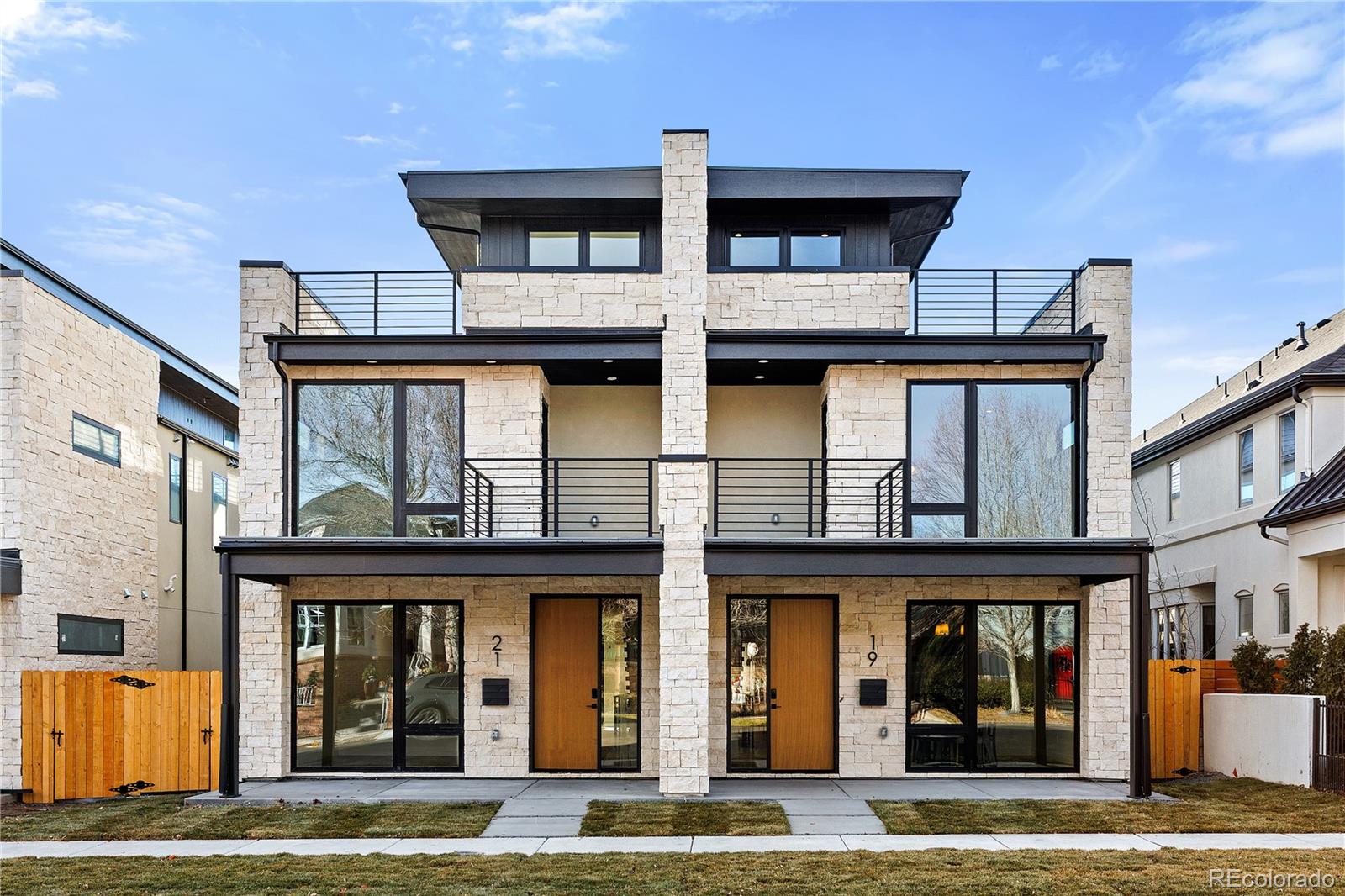 Experience refined Cherry Creek living in this architecturally curated contemporary duplex crafted with PBG’s signature attention to detail. Located less than a 10-minute walk from Cherry Creek’s premier dining and boutiques, this 5-bedroom, 5-bath residence blends organic textures with elevated modern design. The exterior pairs natural stone, warm wood accents, and clean architectural lines for timeless curb appeal. Inside, wide-plank engineered white oak flooring and expansive Andersen windows create a bright, airy ambiance throughout. The main living space is anchored by a floor-to-ceiling fireplace clad in Tumbled Ledger stone, complemented by custom built-ins and a floating wood mantel—delivering warmth without overpowering the space. The chef’s kitchen is a true focal point, featuring custom smoke green cabinetry with brushed brass hardware, integrated Thermador appliances, and a waterfall island wrapped in Arpeggio Leathered stone. Upstairs, the primary suite offers a private balcony, gas fireplace, private bar, and spa-caliber bath finished in Arpeggio Leathered stone. The bathroom showcases fluted accent tile, dual wall-mounted brass faucets, a freestanding soaking tub, glass-enclosed shower with dual heads, and heated floors. A secondary en-suite bedroom and spacious laundry room complete this level. The rooftop level offers flexibility with a bedroom or office, ¾ bath, wet bar, and expansive deck with city views and mountain views—ideal for entertaining. The finished basement with soaring 10-foot ceilings expands the home with a recreation area, wet bar, full bath, additional bedroom, and optional fitness room. A private backyard with covered patio, gas hookup, and TV prewire extends the indoor/outdoor lifestyle. Detached two-car garage includes 220V capability and optional overhead storage. PBG industry leading 2-year builder’s warranty/8-year structural warranty. Prewired for speakers | No HOA | Some photos from 19 S Jackson |Buyer to Verify All Details