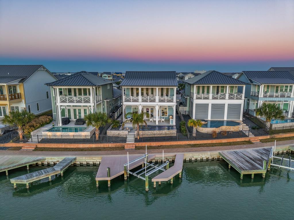 Experience exceptional coastal living at 145 Foxtail Lane, a meticulously maintained waterfront home designed to capture some of the most breathtaking views on the Texas Coast. Overlooking the protected natural beauty of Goose Island State Park, this property offers unobstructed sights and unforgettable sunsets that truly never get old. The spacious covered porch is the perfect place to relax and take it all in, while electronic roll-down shades provide comfort from the sun and added wind protection, rated for 140+ mph, so you can enjoy the space in a wide range of coastal conditions. Inside, the thoughtfully designed floor plan features 12-foot ceilings in the main living areas, an inviting living room with a gas fireplace, and an impressive kitchen with an oversized quartz island and Verona Prestige double oven gas range, ideal for entertaining. The main level includes a private guest suite with an en-suite bath, while the expansive second-floor primary suite offers a sitting area, dry bar, full wall of windows, and direct access to a covered balcony positioned to enjoy the incredible views. The spa-like primary bath features dual sinks, a freestanding tub, walk-in shower, and large walk-in closet. An additional upstairs guest bedroom features a built-in Murphy bed and desk, allowing the space to easily function as a comfortable guest room or home office. Outdoor amenities further elevate the property with a saltwater pool and gas heater, outdoor kitchen, natural gas fire pit, and a composite dock with boat lift ready for days on the water. Additional highlights include a two-car garage with epoxy flooring and climate-controlled tackle room, whole-home Generac generator, tankless water heater with water softener and dechlorinator, reverse osmosis system, hurricane shutters, and elevator prep. This is a rare opportunity to own a truly special coastal property where thoughtful design, exceptional features, and unmatched views come together in one remarkable home.