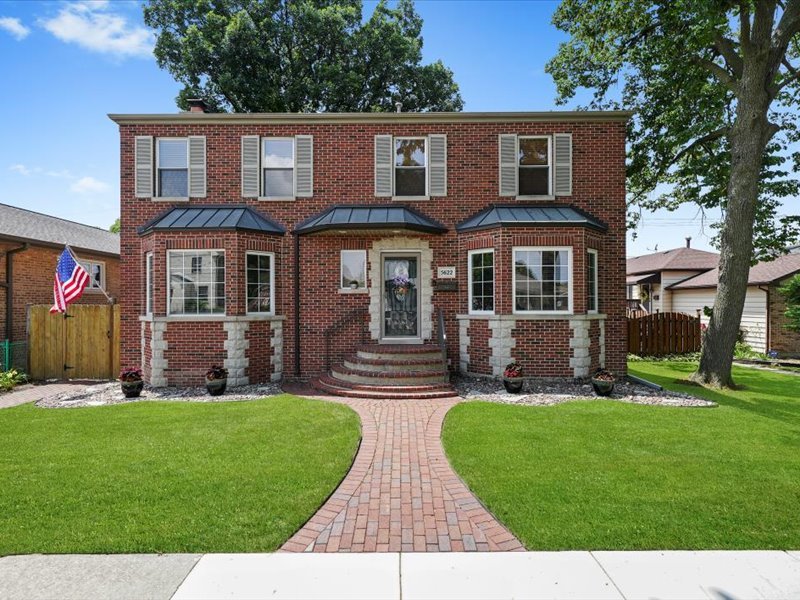 Truly One of a Kind - Custom Built Brick Beauty on an Oversized Lot in Garfield Ridge!  Welcome to this exceptional 4-bedroom, 4-bathroom 2-story home, perfectly situated on a rare 50' x 125' lot. From the moment you arrive, you'll be captivated by its impressive curb appeal, stone-paved walkway, mature landscaping, and timeless brick exterior. Step inside to discover a thoughtfully designed interior featuring oak hardwood floors throughout the main and upper levels. The spacious living room is anchored by a stunning floor-to-ceiling stone wood burning fireplace with a gas starter, creating a warm and inviting atmosphere. Patio doors lead to an expansive wood deck-ideal for entertaining or quiet relaxation. The open concept kitchen boasts cherry wood cabinetry, abundant counter space, a dining island, and custom ceramic tile flooring. Adjacent is a formal dining room, perfect for hosting large gatherings. A main-floor bedroom and full bath offers flexibility for guests or a private home office. Upstairs, you'll find three generously sized bedrooms, two full baths, and a convenient laundry area. The luxurious master suite radiates privacy and romance with second gas fireplace, walk in closet and spa-like bathroom with vaulted ceilings,  skylight, a whirlpool tub, and walk-in shower. The partially finished basement provides additional living space, radiant heated floors, a full bath, and ample storage or workspace potential.  Outside, enjoy a beautifully landscaped backyard oasis with vibrant flowers, a screened-in porch, a private concrete carport, and a heated 3-car garage with extra storage. This meticulously maintained home offers a rare blend of craftsmanship, space, and comfort-perfect for modern living and entertaining. Don't miss this extraordinary opportunity-schedule your showing today!