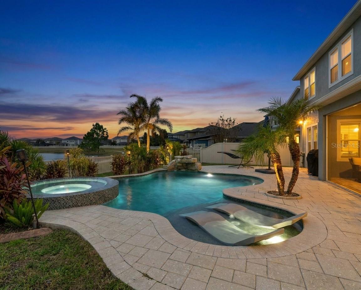 ***New 5 Ton AC installed Feb 2026 & Full Roof replaced January 2025***Welcome to a home that truly feels like a permanent vacation. Perfectly positioned with breathtaking waterfront views, this impeccably maintained residence delivers the Florida lifestyle buyers dream about—peaceful, scenic, and effortlessly elegant.Located in the highly sought-after Long Lake Ranch, this vibrant community offers resort-style pools, a community dock, miles of scenic trails, and a neighbor-friendly atmosphere. Convenience is unmatched with quick access to the Suncoast Parkway, Publix, GreenWise, Starbucks, Panera, dining, shopping, Tampa, outlet mall, medical facilities, pet services, and more.From the moment you arrive, the home’s curb appeal makes a statement. Upgraded landscaping with concrete edging and a fully fenced yard with dual side gates create both beauty and functionality.Inside, a thoughtfully designed semi–great room floorplan welcomes you with an inviting entry and formal dining room featuring elegant tray ceiling detail. Upgraded wood shutters throughout add warmth and timeless style. The heart of the home is the stunning kitchen—complete with granite countertops, staggered white cabinetry, stainless steel appliances, subway tile backsplash, upgraded hardware, a large working island, and an oversized walk-in pantry.A first-floor, possible, in-law suite with guest bath offers flexibility for visitors or multi-generational living. Upstairs, retreat to the private primary suite with tranquil water views, spa-inspired bath, frameless glass shower with rain and handheld heads, dual vanities, and a luxurious soaking tub. A second-floor laundry room adds everyday convenience, along with three additional bedrooms, a full bath, and a spacious bonus room ideal for a media room, game room, home office, or creative space.Car enthusiasts and hobbyists—this garage is a dream. Featuring added A/C, attic solar exhaust fan, 20-amp electrical service, abundant outlets, and overhead storage shelving, it’s designed to impress.Step outside to your personal oasis. The expansive rear lanai overlooks the water and sets the stage for unforgettable entertaining. The upgraded saltwater heated pool and spa offers something for everyone—sun shelf for lounging, spa for unwinding, and a decorative rock waterfall leading into an 8-foot deep pool, perfect for swimming or play. Lush, resort-style landscaping completes this serene backdrop.This home is the total package—location, lifestyle, upgrades, and views rarely found together.Schedule your private showing today and experience why this is truly a must-see Florida retreat.