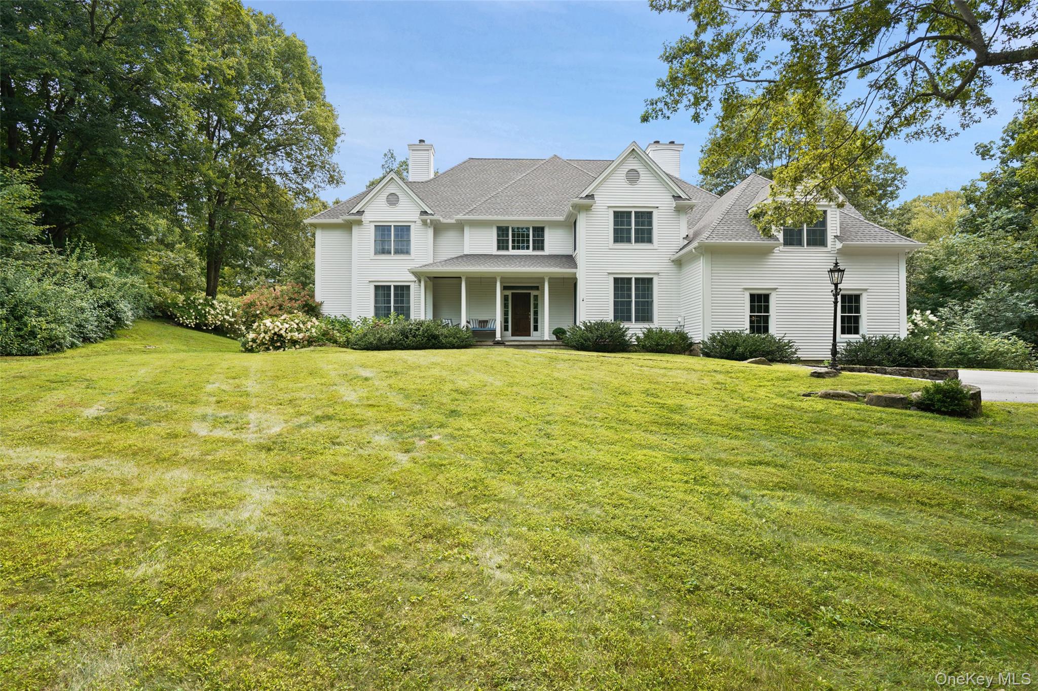 Set gracefully back from a cul-de-sac on 3 private acres, this well-maintained Colonial offers custom details from the original owner. The backyard is a summer oasis with a sparkling pool, multiple lounging areas, and BBQ space, all surrounded by lush, flowering landscaping. Inside, the Living and Dining Rooms share a two-sided fireplace for easy flow and entertaining. The white kitchen with all-new appliances opens to a Family Room with a stone fireplace and built-ins. The first floor also includes a Library with built-in desk, updated powder room, and a spacious mudroom. Upstairs, the Primary Bedroom features two custom walk-in closets and a private bath. A guest suite with en-suite bath, two additional bedrooms, a hall bath, and a large Bonus Room complete the level.The finished lower level offers 1,292 sq ft of flexible space for play, exercise, and storage. Additionally a generator.