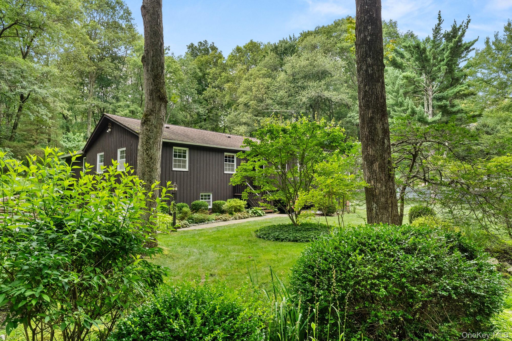 A Picture-Perfect Oasis on 3.46 Private Acres in South SalemWelcome to your own private sanctuary—a meticulously maintained 1,972-square-foot retreat where nature meets elegance at every turn. Built in 1965 and lovingly cared for ever since, this exceptional South Salem property offers the rare combination of tranquil seclusion and premier location in the sought-after Katonah-Lewisboro school district.Your Private Paradise AwaitsStep outside to discover your personal oasis: a serene pond with charming bridge, mature specimen plantings, beautiful stone walls creating intimate garden rooms, and private fencing ensuring complete privacy. The expansive Trex deck features a built-in awning—perfect for morning coffee, afternoon tea, or evening entertaining. The built-in gas grill means you're always ready to host. A beautifully appointed paved and gravel driveway with Belgian block edging and attached two-car garage complete the welcoming arrival experience. Every season reveals new beauty in this thoughtfully designed landscape.Exceptional Interior LivingInside, the home delights with soaring ceilings in the family room, gleaming hardwood floors throughout, and walls of newer windows flooding spaces with natural light. The inviting living room showcases both a fireplace and woodstove for cozy ambiance, with track lighting artfully illuminating your favorite pieces.The updated eat-in kitchen is a chef's dream featuring custom cabinetry, a professional Wolf gas range, built-in storage, and effortless flow to the dining room. The formal dining room offers built-in storage and sliders opening to your private deck oasis—seamless indoor-outdoor living at its finest.Thoughtful Bedroom WingThe primary suite is your personal retreat with hardwood floors, double closets, ceiling fan, sliders to the deck, and en-suite bath with shower and heated flooring. Three additional well-appointed bedrooms include one currently used as an office with custom built-in shelving—ideal for today's work-from-home lifestyle. The second full bath features heated towel bars, classic wainscoting, and a tub/shower combination. Generous closets and a full attic provide abundant storage.Modern Conveniences & Versatile SpacesPeace of mind comes standard with central air conditioning and an automatic whole-house generator. The large, bright walk-out lower level with windows offers endless possibilities for recreation, fitness, or additional living space.The Perfect LocationEnjoy the best of both worlds: a peaceful, private setting in top-rated Katonah-Lewisboro schools, minutes from restaurants, shopping, and Metro-North train service. Whether it's winter snow, spring blooms, summer entertaining, or fall foliage—this home shines in every season.This is more than a house—it's a lifestyle. Your South Salem oasis awaits.