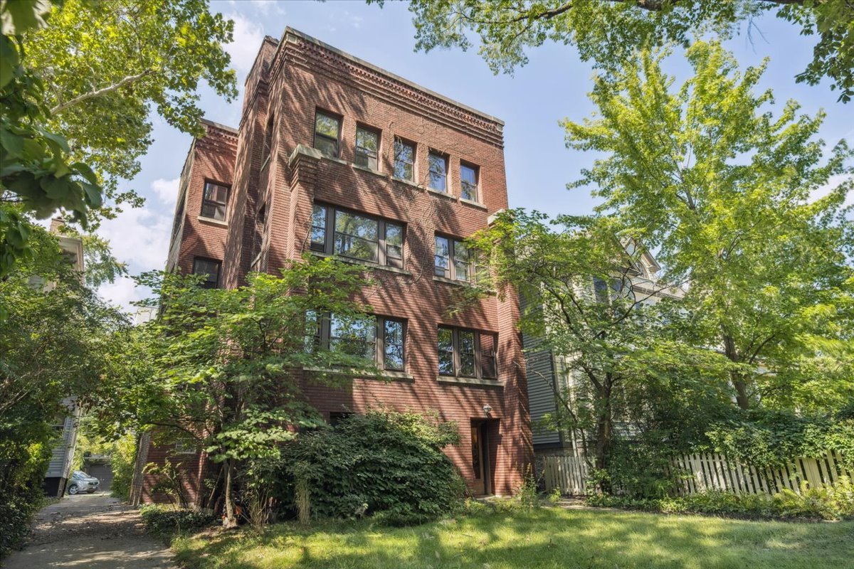 This beautifully updated and spacious 4-bedroom, 2-bath condominium offers an ideal blend of vintage charm and modern comfort. Perfectly situated just steps from the heart of the University of Chicago campus, this home occupies the entire high first floor of a classic Prairie School-influenced brick building. Enjoy abundant natural light and tranquil views from every room in this bright and airy residence. Rich with original character and freshly painted, the unit features hardwood floors throughout, a striking Roman brick fireplace, and gleaming woodwork that adds warmth and elegance. The kitchen has been enlarged and the bathrooms have been tastefully renovated. Additional conveniences include air conditioning, a large shared laundry, generous basement storage, a lush shared yard, and a dedicated one-car garage. This self-managed, well-maintained building offers a strong, stable association in a picturesque, residential neighborhood - perfect for those seeking charm, space, and a prime location in one of Chicago's most historic and picturesque neighborhoods.  Welcome home!