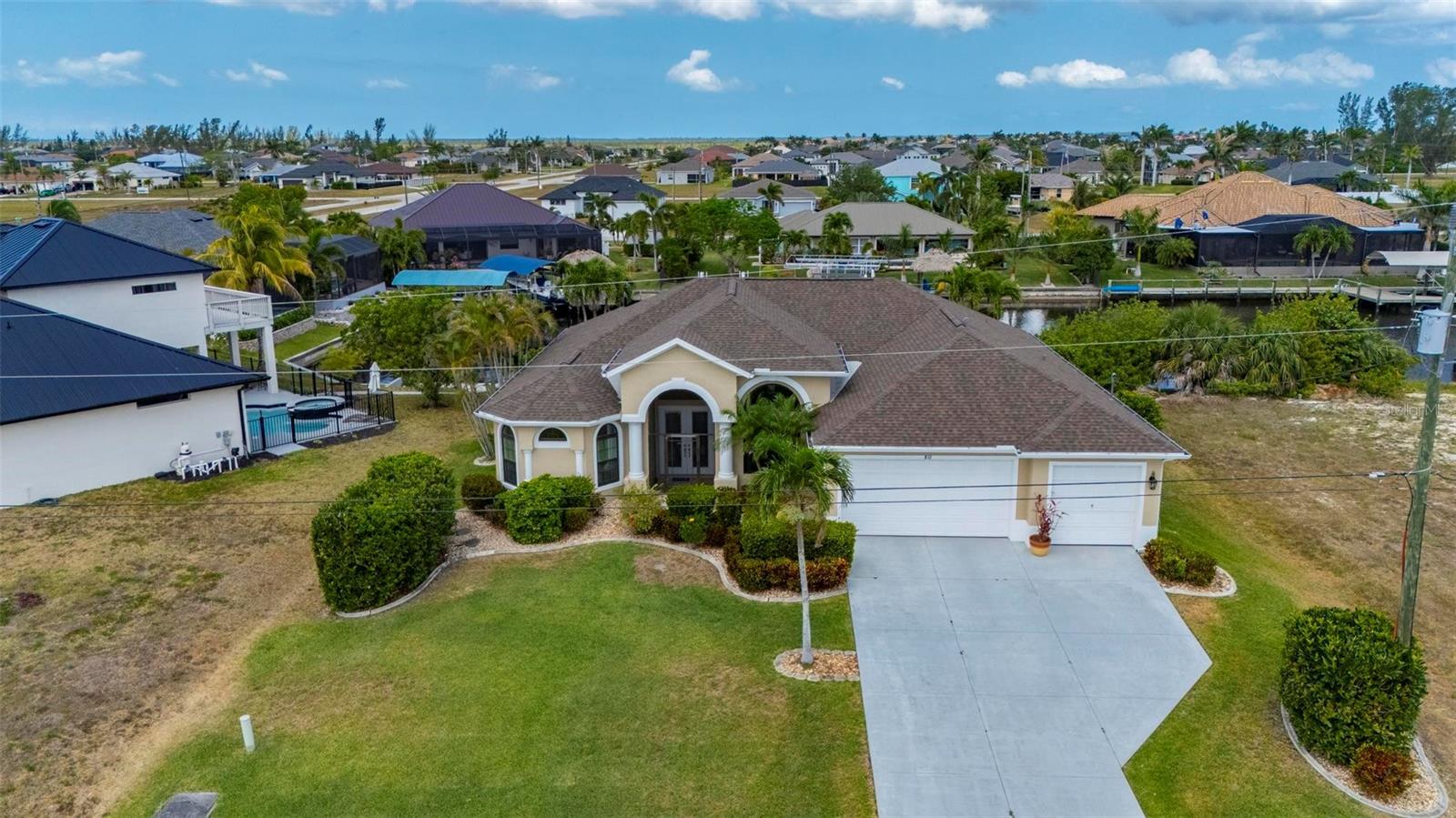 One or more photo(s) has been virtually staged. Experience the ultimate in Florida living with this exquisite furnished 4-bedroom, 2.5-bathroom waterfront pool home with jacuzzi and 3-car garage, perfectly situated in the heart of Cape Coral—and not located in a flood zone. From the moment you arrive, the lush, meticulously maintained landscaping sets the tone for what lies beyond the grand double-door entrance. Inside, you’re welcomed by soaring ceilings, abundant natural light, and stunning canal views through expansive glass French doors.

The chef’s kitchen is a dream, offering a spacious cooking island, abundant cabinetry, and a large walk-in pantry with automatic lighting. Just off the kitchen, a spacious laundry room with a deep freezer adds convenience and storage. All four bedrooms are generously sized with large closets, while the luxurious primary suite features an oversized spa-style bathroom with a walk-in shower and dual showerheads—ideal for unwinding at the end of the day.

Step out back and enjoy your own private resort-style oasis. The heated pool features built-in bar stools, and the heated jacuzzi provides the perfect spot to relax while soaking in peaceful water views. An outdoor half bath adds convenience for guests, making this space ideal for entertaining. For boating enthusiasts, the property includes a 33-foot dock with a 10,000 lb. boat lift, which extends 20 feet into the canal for easy access to open water.

This turnkey home also includes numerous recent upgrades: a whole-house reverse osmosis system, electric storm shutters (2023), 16 impact windows (2023), a new roof (2021), a full HVAC system (2016), an irrigation system, a boat lift canopy (2022), and a concrete seawall (2004). The 3-car garage is fully equipped with a generator hookup, adding peace of mind. A full home and pool inspection and recent appraisal (Feb 2025) provide added confidence for buyers.

Located close to top-tier dining, shopping, boating, and Florida’s beautiful beaches, this exceptional home truly offers it all. Schedule your private tour today—this is Florida waterfront living at its finest!
