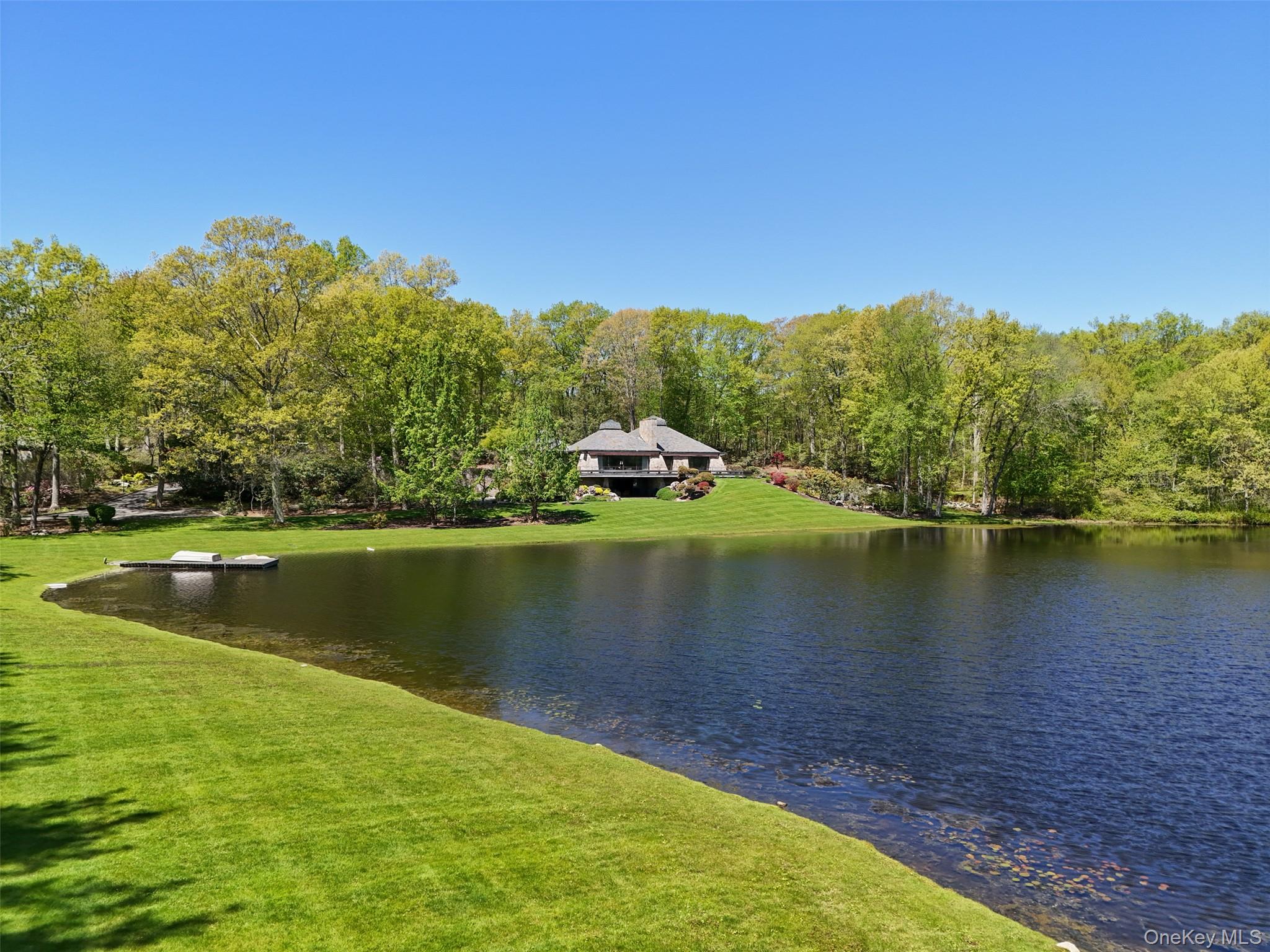 EASTLAKE. Nearly 39 serene acres offering the ultimate in privacy. Long, gated drive over rushing stream and through manicured grounds. Remarkable estate compound owned for years by renowned fashion designer as a family residence. Impressive architect-designed Stone and Country House positioned to overlook a private eight-acre lake. Striking and sophisticated Contemporary with elements of a Mid-Century Modern. Impressive rooms with natural finishes of fine woods and hand-cut stone. 5500 square feet of airy, loft-like living space positioned to capture views of the water. Beautifully scaled main rooms with vaulted ceilings, finished in warm woods, stone and hardwood floors and walls of glass. Striking Living Room with stone fireplace and vaulted ceiling lit by a modern cupola. Doors to wrap-around porch for fantastic indoor-outdoor living. Open-concept Dining Area also with water view, perfectly scaled for entertaining. Sleek Kitchen designed for the consummate chef. Private Office with conference area and wet bar. Lower Level Family Room for more casual everyday living. Spacious first floor Primary Suite with ample closets and private Bath. Four additional Bedrooms, most with en-suite Baths. Breathtaking grounds amid dramatic rock outcroppings with stone walls and terraces, an incredible array of flowering plantings, rare and specimen trees and rolling lawns down to the water. Fenced garden for flowers and seasonal produce. Lakefront dock, heated Swimming Pool with Pool House and privately sited Tennis Court make for an incredible sporting lifestyle. Separate building complex with a Three-Bedroom, fully equipped Guest House, Garages for six-plus cars and equipment storage. The perfect, peaceful refuge.