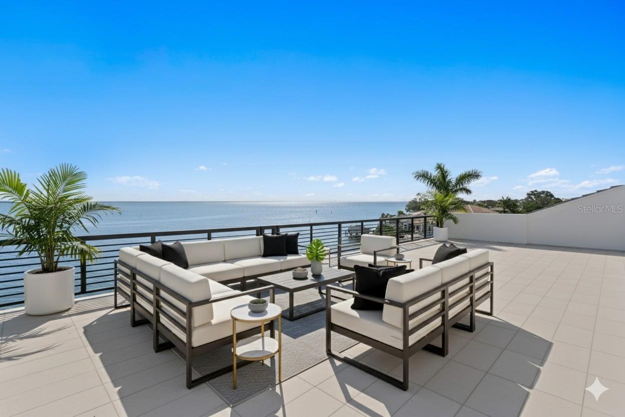 Recently completed to the highest standards, this stunning new construction Venetian Isles waterfront residence blends refined luxury with cutting-edge engineering. Built on pilings and reinforced with rebar/concrete, this elevated home offers unmatched strength, stability, and peace of mind. Poised gracefully at the edge of Tampa Bay, enjoy sweeping, uninterrupted views that extend across the glistening water to the skyline of St. Petersburg. Built by Tide Homes, a professionally designed interior provides a sophisticated aesthetic and curated elegance. From the moment you step inside, you’re welcomed by warm Chesapeake hardwood floors and a serene palette of premium finishes. The expansive main living area delivers sweeping floor-to-ceiling water views and a dramatic gas fireplace and feature wall which integrates a glass-enclosed wine cellar that anchors the formal dining area. A sleek chef’s kitchen is crafted with carbon-neutral Dekton countertops and backsplash, Thermador and Bosch appliances, a butler’s pantry/full prep kitchen with additional dishwasher and refrigerator, along with an expansive waterfall island and access to the gracious main terrace with outdoor kitchen. The main living level also features 3 ensuite guest bedrooms and one of 2 laundry rooms with LG appliances. Upstairs, a versatile bonus room provides the perfect location to relax, indulge in a competitive game night, or entertain with ease. A custom entertaining wet bar and media wall set the tone, while expansive glass doors flow to the waterfront terrace, along with spiral stairway access to the rooftop terrace and unmatched panoramic views. Through the double doors, a private primary suite greets you with spectacular views, an impressive custom his and her closet/dressing room, along with a spa-inspired bath offering backlit mirrors, expanded glass shower and deep soaking tub. This private level also features a powder bath and laundry room, along with an additional ensuite guest bedroom and walk-in closet. Experience exceptional Florida living outdoors, with over 750 feet of covered lanai space, saltwater heated pool and spa that overlook the glistening bay, along with a private dock for endless water recreation. From the fortified piling construction and 3-stop commercial-grade glass elevator—to marine-grade outdoor cabinetry, dual laundry rooms, and a 3-car garage, this modern waterfront escape delivers uncompromising strength with premium building compliance, PGT impact-rated windows and sliders, and impact garage doors. Located in one of St. Petersburg’s finest neighborhoods, enjoy convenient access to parks, recreation and award-winning beaches, while only minutes to downtown St. Petersburg’s vibrant arts and culinary destinations.