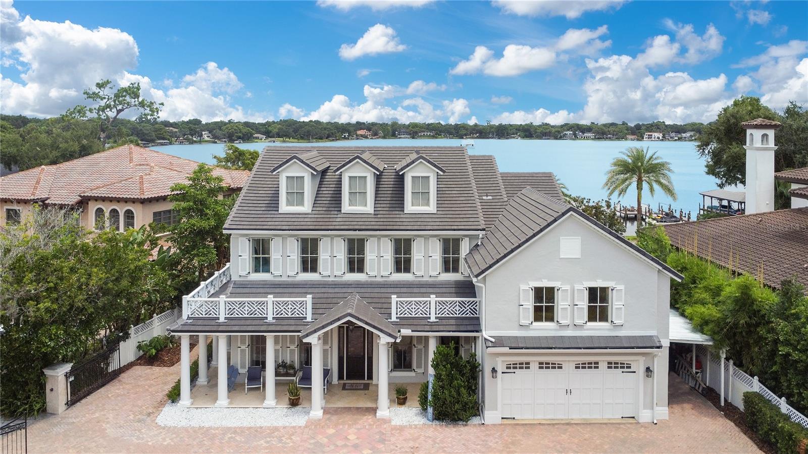 The Winter Park Chain is the context; the shoreline of Lake Minnehaha is the setting. A three-story, columned home opens with an honest, crafted tone: new low-profile concrete tile roof, operable cypress shutters with hand-forged hardware, Chippendale balustrades, and a beveled front door offering almost 6,200 sq. ft. curated for light, views, and everyday lake living. Inside, the home is bright and airy—sunlight does the work here. A direct foyer sightline leads you to a rear wall of French doors that draw in a calm, even glow of natural light across heart-of-pine floors and disciplined millwork: raised-panel wainscot, multi-step crown molding, and architectural beams. Those doors open to a full-length covered lanai; beyond, a heated saltwater pool and spa step down to a deep backyard and a private dock with a covered boat slip and adjoining lounge deck. The kitchen is built to perform so life feels easy. Morning coffee, weeknight pasta, Saturday crowds, it handles all of it. Sub-Zero refrigeration with additional refrigerator drawers, a Thermador six-burner gas range, two dishwashers, and a warming drawer. Granite counters surround a prep island with rinse sink; the peninsula takes the laptops and late plates. A dry bar with wine cooler ties to the dining room for effortless pours and keeps glassware close at hand. Just off the family room, the primary suite claims a quiet corner and opens to the lanai; coffee at sunrise, warm light at day’s end. A large custom walk-in closet answers storage; the bath finishes the suite with tumbled marble, Kohler fixtures, and a cast-iron vintage tub. At the center of the first floor, a deliberate service run keeps daily life organized: powder bath, temperature-controlled wine cellar, a straight sightline to the first of two laundry rooms and the garage entry ending at a private interior stair to a secluded in-law/guest suite with its own full bath. It’s independent, quiet, and ideal for long stays or live-in support. The main stair brings you to a second level arranged with intent. One wing holds three bedrooms around a shared bath. An office corridor carries you to the lake-view great room under a coffered ceiling; triple French doors open to the full-length upper veranda. Another bedroom on this wing enjoys its own veranda access with a full bath close by. Above it all, the third floor is a generous, flexible loft fit for a screening room, billiards or game lounge, studio, gym, or a collector’s library with practical storage tucked to the edges. Quiet systems match the craft: Cat-5 wiring, surround sound, central vacuum, and two laundry rooms. Recent updates keep the essentials current: new HVACs (2020, 2021) and a new dock (2024). Zoned for Maitland Middle and Winter Park High, this home is tuned to everyday rhythm: water out back, light throughout, spaces that work the way you live. From lanai shade to the last light on the lake, it delivers on its promise—an honest, crafted place where the architecture serves the life it keeps.