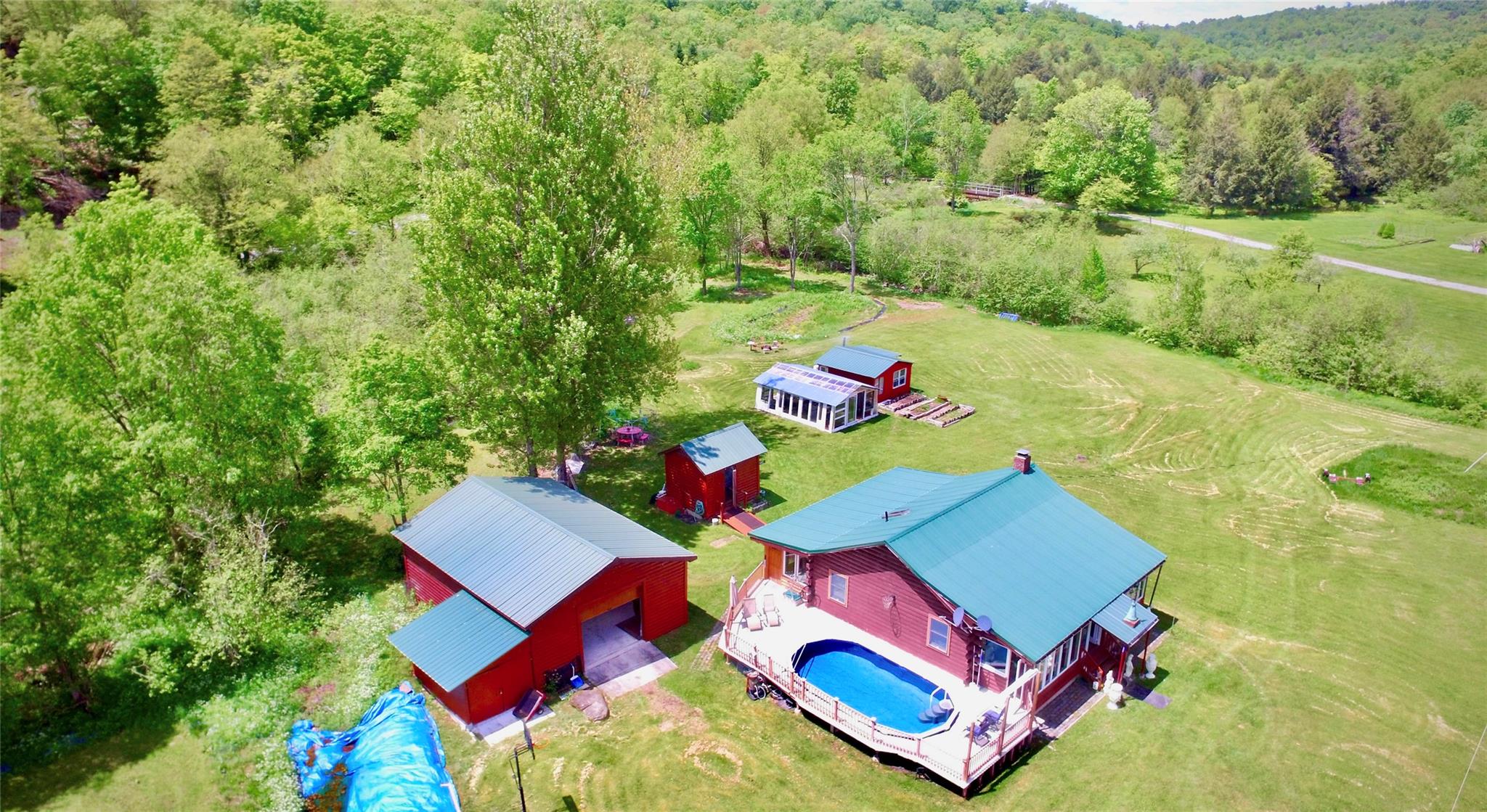 Aerial view of property and surrounding area featuring a forest and a pool area