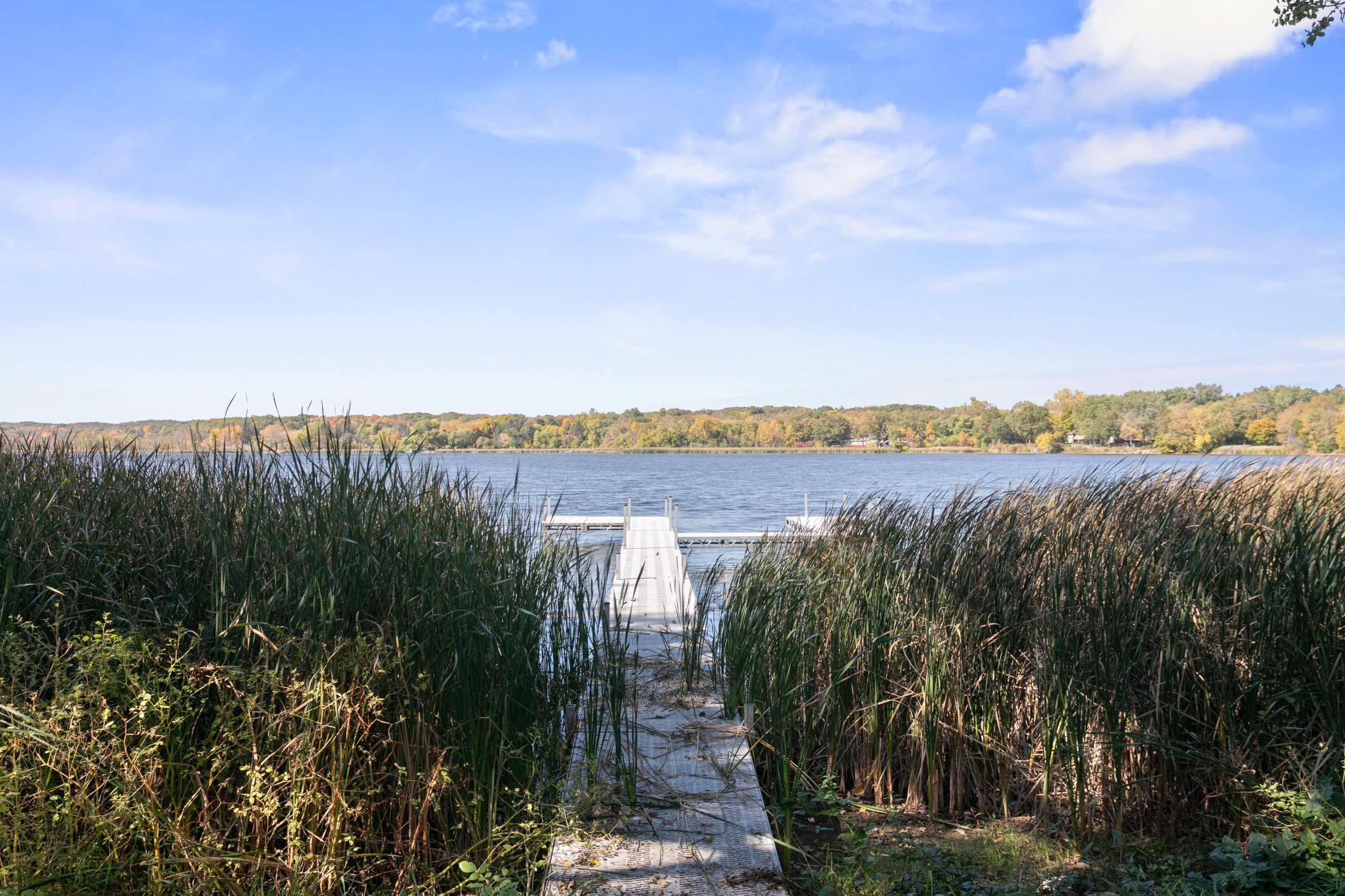 Wake up every morning to beautiful morning light and end your days watching spectacular sunsets over highly desired Kraemer Lake. This stunning 3-bedroom plus office, 2-bathroom home sits on a rare, perfectly level 0.5-acre lot with 100 feet of shoreline, offering the ultimate blend of peaceful lakefront living and incredible convenience—just minutes from charming St. Joseph, St. Cloud, and easy I-94 access.Designed to maximize its setting, the home features an east-facing front porch perfect for your morning routine, while the main living spaces open up to panoramic lake and sunset vistas. The modern kitchen features premium Cambria quartz countertops, rich maple finishes, a deep basin sink, and upgraded, lake-friendly luxury plank (LVP) flooring. A flexible lower level room serves as the perfect dedicated home office, while the private primary bedroom upstairs treats you to gorgeous lake views every single morning.The outdoor lifestyle here is unmatched. Enjoy a quiet cup of coffee on the screened-in back porch as the water creates a serene backdrop, or head down to the massive private dock (a negotiable item with the property) for a day on the lake. In the evening, the walk-out basement leads seamlessly to the patio fire pit, making it the premier spot to gather and watch the sun dip below the horizon. Don't miss your chance to own a slice of waterfront paradise—schedule a showing before this one is gone!
