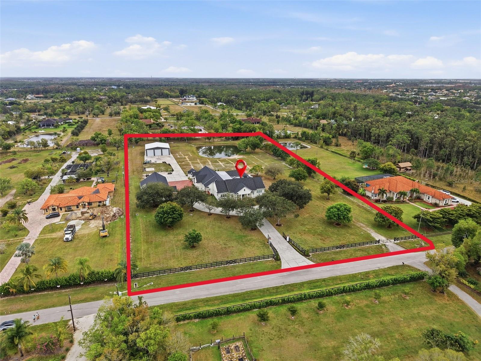 One or more photo(s) has been virtually staged. This exceptional estate offers a rare combination of luxury living, advanced construction with numerous appointments to detail, and unmatched versatility on a pristine 5-ACRE property with a pond (NO WETLANDS). Located just minutes from shopping, restaurants, and the international airport, you will have the feel of privacy and seclusion with everything you need at your fingertips. Designed for both everyday comfort and grand-scale entertainment, the home features a spectacular resort-style outdoor oasis (2025), complete with a HEATED, SALTWATER POOL, expansive 4,000 sq. ft. SCREENED LANAI, OUTDOOR KITCHEN, bar area, pool bath, and multiple covered seating spaces creating a true private retreat. Inside, refined craftsmanship and thoughtful design are showcased throughout. The gourmet kitchen and BUTLER PANTRY are equipped with premium high-end appliances, including a 48” GAS DACOR COOKTOP with DOUBLE OVEN and built-in SUBZERO REFRIGERATOR, abundant storage, and generous prep space, ideal for hosting and daily living. The luxurious primary suite offers a spa-like bath, custom closets, and modern finishes overlooking your outdoor oasis.  Upstairs, you will find an entertainer's dream with a full-size HOME THEATRE- 133” screen, 8-person theatre seating, top of the line sound system & built-in projector. GAMING AREA with Pool Table, 2 TVs & video game area. Additional highlights include built-in wine nook with wine refrigerator, tech center, office area with conference space & home gym.  Ideal for multi-generational living or income potential, the property includes a private suite with its own entrance, kitchen, living space, and laundry. Advanced smart-home technology by Crestron, Mid Atlantic, Lutron & Sonos include integrated sound systems, security, and lighting controls to enhance comfort and efficiency throughout. Car enthusiasts, business owners, or hobbyists will appreciate the impressive ACCESSORY BUILDINGS, including a high-clearance Bus (RV) BARN and a large WORKSHOP/GYM/OFFICE COMPLEX with vehicle lift, climate control, and additional office and conference space. Built with ThermaSteel SIP construction, the home offers superior energy efficiency, impact-rated features, whole-house RO water system, a backup generator, and multiple HVAC systems. Zoned AG – you could have a farm or run a business; the sky is truly the limit with gated access and the ability to subdivide approximately 1.5 acres. NEWER ROOFS (2023), NEWER HVAC units (2018-2024- 6 units), & NEW POOL (2025). This one-of-a-kind property delivers an exceptional opportunity to own a property that truly has it all: luxury, flexibility, and a lifestyle without compromise.