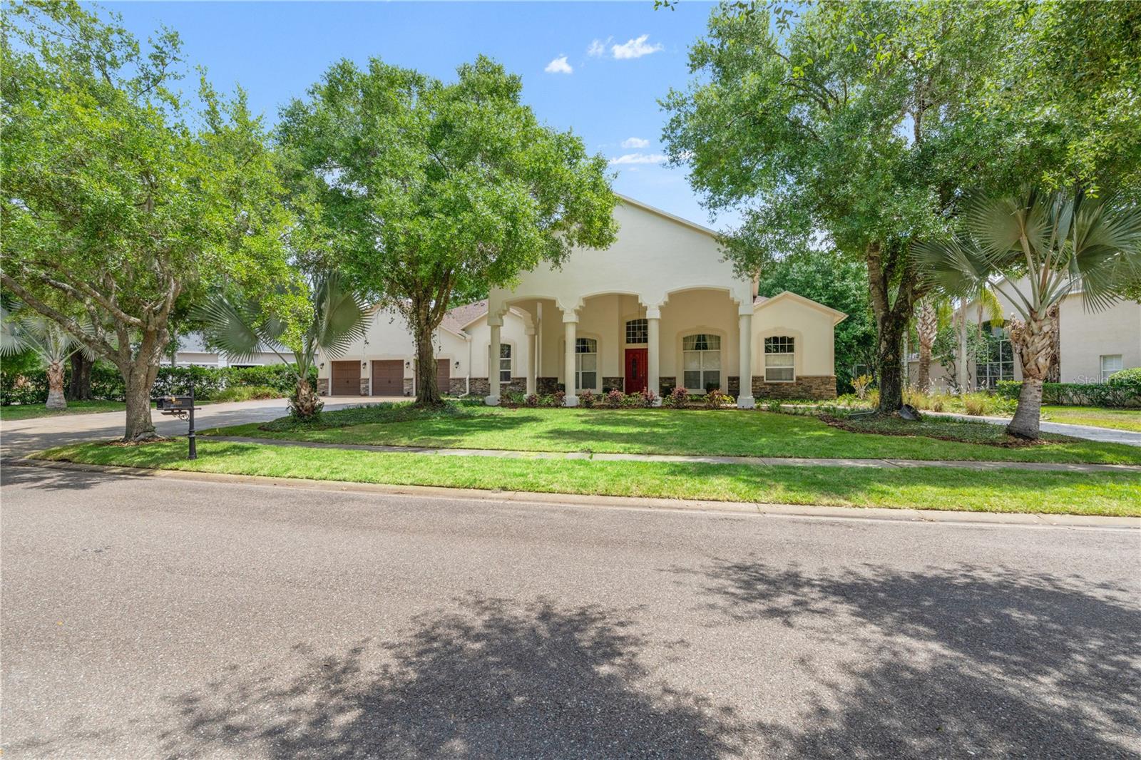 Exceptional opportunity to own one of Tampa Palms’ most distinctive custom waterfront homes, perfectly positioned on an oversized homesite in the gated village of Huntington. Set on an impressive homesite, this residence immediately stands apart with its architectural presence, welcomed by a stately portico, circular driveway, and elegant porte'-cochere, all framed by beautifully maintained landscaping that creates a warm and lasting first impression.Step through the double wood and leaded glass doors into a light-filled interior where dramatic architectural details immediately take center stage. Soaring 14 foot ceilings, extensive crown molding, and expansive sightlines create a sense of openness and scale, while custom 10 foot sliding glass doors draw your eye straight to the outdoor living space beyond. The formal living and dining areas are anchored by an elegant foyer and designer lighting, offering a grand yet inviting introduction. A private den with double door entry provides the perfect space for a home office or study.The home flows effortlessly into a stunning main living area designed for both comfort and impact, where rich finishes, large windows, and natural light come together to frame tranquil water views. At the heart of the home, the kitchen offers both function and style with 42 inch cabinetry, granite countertops, a built-in desk, gas cooktop, and a spacious nook overlooking the pool and water. The primary suite is privately positioned and thoughtfully designed as a true retreat, featuring a sitting area, direct access to the lanai, dual walk-in closets, and a well-appointed bath with garden tub, separate shower, and dual vanities with granite countertops.Additional bedrooms are well proportioned, and a dedicated office adds flexibility for today’s lifestyle. A fifth bedroom offers even more versatility and may easily be used as a bonus room, media space, or guest retreat depending on your needs.This home has been meticulously maintained and extensively upgraded, with over $330,000 in improvements including a newer roof in 2022, updated air conditioning systems in 2023, remodeled kitchen and bathrooms, resurfaced pool and deck, updated landscaping, and more.Enjoy a private setting with a resurfaced pool and spa, an updated pool deck, and a replaced pool cage with recent rescreening, all overlooking peaceful water views and a spacious backyard.Ideally located in the heart of New Tampa, residents enjoy access to Compton Park and all the amenities Tampa Palms is known for, along with close proximity to top rated schools, major hospitals including Moffitt Cancer Center, AdventHealth, and the VA Hospital, as well as USF, I 75.