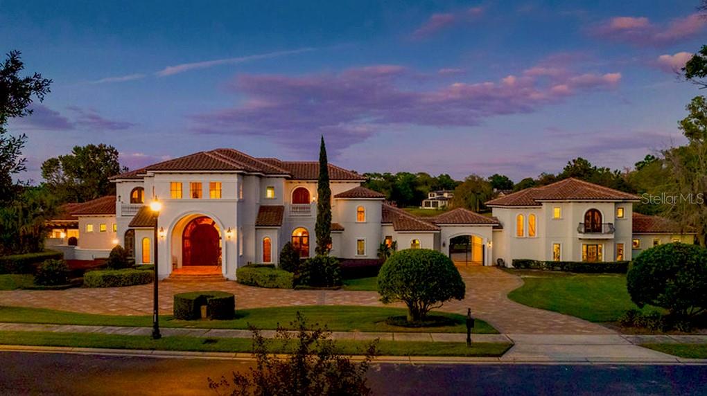 Experience the pinnacle of luxury living in this one-of-a-kind waterfront estate, ideally positioned on a double lot within the prestigious guard-gated community of Lake Markham Preserve, just minutes from Lake Mary, Longwood, Heathrow, and Sanford. This magnificent 5-bedroom, 7-bath, 6-car-garage residence spans over 2 acres of manicured grounds, offering a seamless blend of wellness, recreation, and refined sophistication.
A grand two-story foyer welcomes you with a sweeping double staircase, soaring ceilings, and breathtaking views of the sparkling infinity-edge pool that appears to flow directly into the lake. Exceptional craftsmanship defines every space, from the rich wood detailing in the executive office to the elegant finishes throughout the formal living and dining rooms.
The primary wing is a private sanctuary devoted to relaxation and health, featuring sea-salt walls and a sea-salt therapy room—a luxurious and restorative feature known to purify the air, improve respiratory wellness, and promote deep relaxation. French doors open from the primary suite and home office to a Tuscan-style courtyard, creating a tranquil retreat complete with landscaping and a soothing water feature. Inside the suite, enjoy a massage room, sauna, private fitness studio, and spa-inspired bath — your personal wellness haven.
The open-concept chef’s kitchen flows effortlessly into the spacious family room and entertainment wing, where you’ll find a game room with a private bowling lane, ideal for hosting and entertaining. Large windows and glass doors fill the home with natural light and frame sweeping views of the pool, courtyard, and lake.
The second floor of the residence continues the home’s sense of grandeur and comfort, offering a private retreat for family and guests alike. Upstairs, you’ll find three beautifully appointed en-suite bedrooms, each with its own luxurious bath and thoughtfully designed to provide privacy and comfort. The spacious theater room is perfect for movie nights or sporting events, creating a cinematic experience within the comfort of home. A large balcony stretches across the back of the home, offering sweeping views of the infinity-edge pool, lush grounds, and shimmering Lake Markham—the perfect setting for morning coffee or evening relaxation while taking in the tranquil lakefront panorama.
Outdoors, the resort ambiance takes center stage. A heated infinity-edge pool and spa, and summer kitchen create the perfect setting for gatherings and sunset dinners. A private boat dock with a covered lift provides direct access to Lake Markham, inviting peaceful mornings on the water or evenings spent boating under the stars. Recreational features abound, including a lighted basketball court, professional shuffleboard court, tiki hut cabana, all within fully fenced and landscaped grounds offering privacy and serenity.
A detached guest house provides comfort and independence for family or visitors, featuring its own living area, kitchen, and bath. Additional highlights include a custom wine cellar, whole-house generator, circular driveway, and ample guest parking.
Designed for the discerning professional who values both health and sophistication, this estate seamlessly combines wellness-oriented design, European-inspired elegance, and resort-style living in one breathtaking lakefront retreat — a true masterpiece where luxury meets longevity.