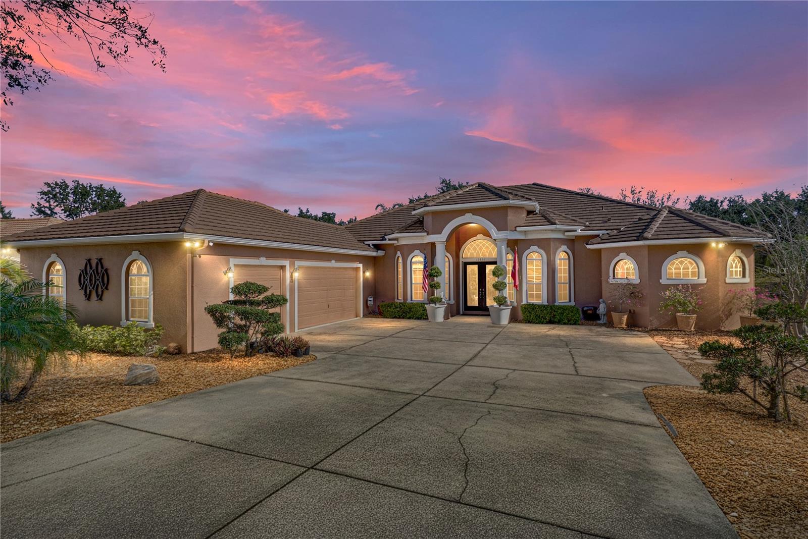 This is the kind of home that makes you want to cancel weekend plans. Set behind the gates of the amenity-filled Lake Jovita community and with tranquil golf course views, this expansive 4 bedroom + office, 3 bath, 3 car garage pool home offers 3,297 sq ft of thoughtfully designed living space on over half an acre, with attention to detail you feel the moment you arrive. A tropical, well-manicured front yard and pillar-accented double entry doors with a decorative glass inlay create a stylish and welcoming first impression. Inside, the layout opens wide and flows effortlessly, with a spacious living room measuring 21x22 and framed by quadruple sliding doors that draw your eye straight to the pool and outdoor entertaining area. The connection between the living room, formal dining area, and kitchen makes the home feel open yet grounded, while tray ceilings with LED lighting, plush carpet, crown molding, and elegant light fixtures add warmth without feeling overdone. The kitchen sits at the center of it all and is designed to be used and enjoyed. Granite countertops, a full stainless steel appliance package, generous cabinetry, expansive prep and serving space, breakfast bar seating, and a casual dinette create a space that works just as well for quiet mornings as it does for hosting. A private office is positioned near the front of the home and conveniently close to the primary suite, making working from home practical and comfortable. The primary suite itself is a true retreat, offering plush carpet flooring, two large walk-in closets, and direct access to the pool. The ensuite bath is beautifully arranged with a central jetted tub, dual sinks with ample counter space, a linen closet, water closet, and a walk-through shower with dual showerheads that feels like a relaxing daily reset. Secondary bedrooms are thoughtfully separated for privacy. Bedroom two is tucked into its own guest wing with an ensuite bathroom and sliding door access to the pool, lending itself perfectly to guest accommodations, a media room, or a flexible second living space. Bedrooms three and four are located down a separate hallway near the third full bath, creating a functional and comfortable layout. An interior laundry room with a utility sink and extensive cabinetry adds everyday ease, while the oversized 3 car garage provides plenty of room for storage or golf carts. Outside, the home truly comes into its own. The expansive paver pool deck has been newly sealed and upgraded to impress, featuring a bar with a refrigerator and seating, a pergola positioned to take in the golf course views, and a sparkling heated saltwater pool and spa with upgraded tile and new equipment. This is a space designed for long afternoons, sunset conversations, and effortless entertaining. Luxury living in Lake Jovita means enjoying access to a playground, park, pickleball court, and walking trails. Optional membership packages at the Lake Jovita Golf and Country Club include access to 2 18- hole world-class golf courses, a Jr. Olympic size swimming pool, a restaurant, a clubhouse, a fitness center, a pro shop, and more! If you have been searching for a well-proportioned home with golf course views, a refined interior, and a standout pool setting on a generous homesite, this Lake Jovita residence delivers- call us today for your private tour!