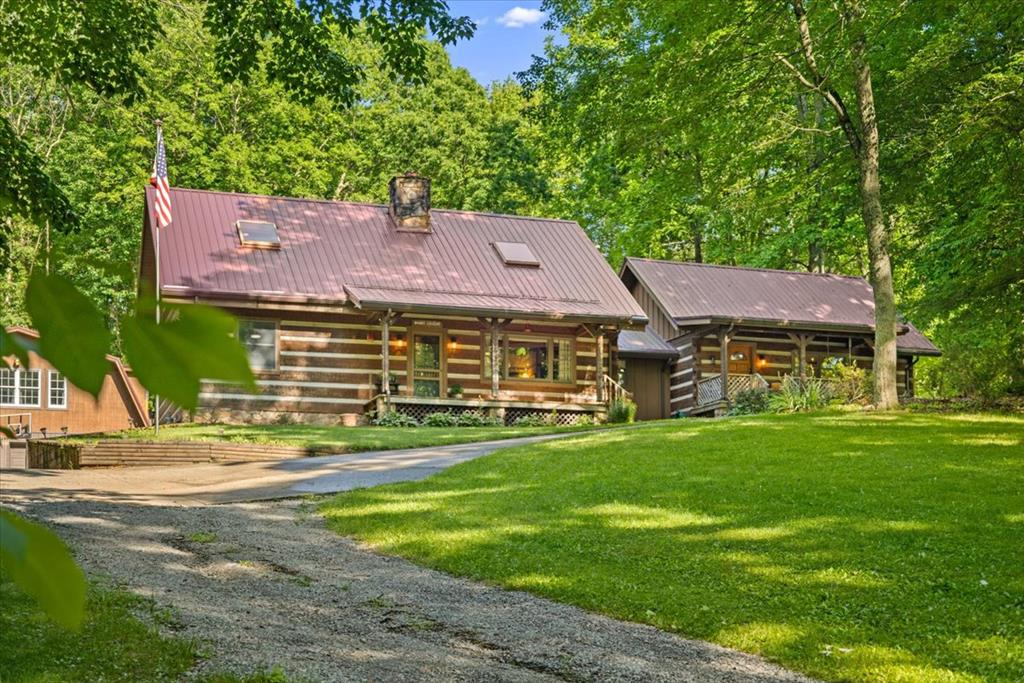 Escape to the tranquility of nature with this charming log home, nestled among mature trees on a beautifully maintained, park-like property. As you pass through the stone columns at the entry way, you immediately are impressed with the classic log home that has inviting covered porches. This unique residence blends rustic character and everyday comfort. This home is situated on 9 acres that create the perfect setting for relaxing, entertaining or enjoying outdoor activities. Attached is a one-bedroom guest house that could be used as in-law quarters, Airbnb or easily modified to add additional living space to the main dwelling. As you enter the home, you feel the warmth and coziness of cabin decor. The stunning stone fireplace is the focal point of the interior. Current owners reconfigured the kitchen and dining area to be more user friendly for entertaining family and friends. Updated stainless steel appliances and new countertops with bar seating add to the functionality. Two bedrooms and one bath can also be found on the main level. As you walk up the hand-hewn style steps to the loft, you can see the majestic craftsmanship in this home. Large open loft master suite boasts of vaulted ceilings, skylight, ensuite bath and reading nook. The basement offers many possibilities for use, even a 5th bedroom if needed. As you venture onto the 9-acre parcel, you will find that the current owners have literally turned this space into an amazing recreational and therapeutic retreat. It includes a 2-car garage with a bonus room above. The wooden lighted walkway leads to an entertainment style metal building with an outdoor firepit and bar. Further along, there's a one room bunkhouse with an attached shower and privy. In addition, a nautically decorated one room guest space known as the "Boathouse." As you continue your journey you will hear the mountain stream and experience the solitude of nature. Did we mention the 150' zipline already in place?! Opportunities abound......
