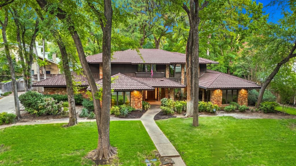 Architecturally Styled- influence of Frank Lloyd Wright type of Design. Upscale Overton Woods, a prestigious desired neighborhood! This home was designed to enjoy your life & living. Beautifully built in this location to showcase the home and landscaping-with accent lighting. Live, Dine and Intertain while viewing a serene landscape that is peaceful & relaxing. Immaculately well maintained - One-Owner home designed with amazing floor to ceiling Pella Double pane windows & sliding glass doors through-out.  All Sand Stone (walls, columns- fireplace etc.) came from Ranger Texas. Metal Roof, Wood Beams- true workmanship through-out this home, beautiful wood flooring. Three Ensuite bedrooms-upstairs- all bedrooms- Beamed Shadow Box Ceilings. Primary bedroom closet-is top of the line- Maplewood- frosted glass doors- to hang your clothes, shoe rack - built in drawers etc. Shower and jetted bathtub.  Large Gameroom-with bar. 1 half bath downstairs. Also Spacious room was used as an office- Need a playroom,workout room? Make this house yours! Large Formal dining room. Updated kitchen- 2024- Alderwood Cabinets, Jenn Air Appliances, Sub-Zero Refrigerator, New Countertops. Ash Wood stairs (carpet over wood) 2nd story- ALL ENSUITES have balconies- 60 ft of balconies. Quiet neighborhood, convenient location to dining and shopping. Three HVAC's zoned-2 downstairs & 1 upstairs. Backyard-room for a pool, parties, pets- children- enjoyment. Large covered Patio. A Fabulous opportunity to live, love and enjoy this showcase home!