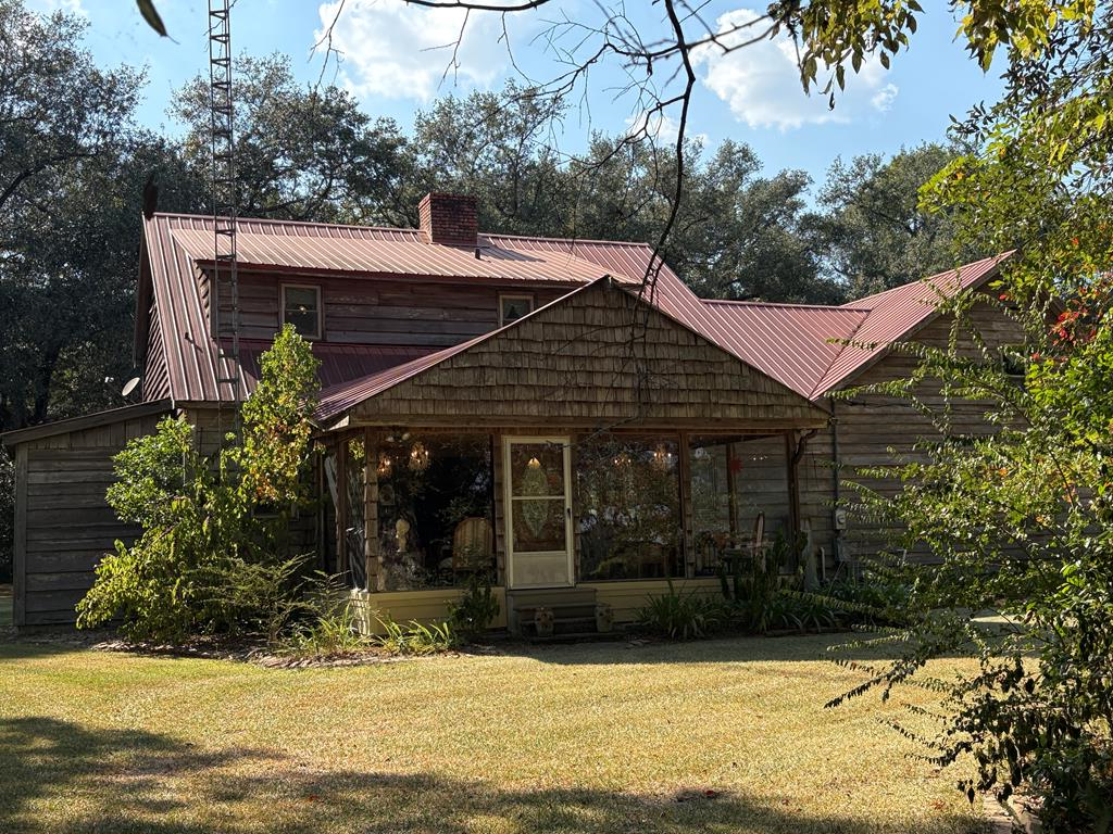 The unique quality of this home is its mixture of woodsy blended beautifully with crystal chandeliers in just the right places!!  It's coziness is very obvious and the whole home is built with cypress wood, some of which has planks that are about 18" wide!  Even the doors are cypress and the knobs are perfect and reminiscent of the old days.  It's very SOLID!  There's a step in shower upstairs, and a HUGE bedroom up there also!  A favorite place to be in this wonderful home, is in the gorgeous SUNROOM!!  It's large, glass panels from floor to ceiling, make it as though you are outside with a peaceful and amazing view.  The hours are endless that are enjoyed there.  The kitchen has upgrades of hard surface countertops and new appliances and the chandeliers are in these downstairs living areas that add just the right touch of sparkle!!  Outside is the wired workshop that is very spacious and equipped with shelving for everything  you need for your craft projects and lawn care.  The lot is really beautiful with that true southern feel of gentle breezes among the stately trees and comfortable terrace to enjoy!  Please make an appointment and come see for yourself.