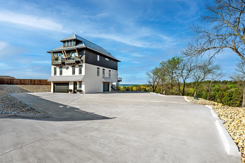 Experience elevated lake living at its finest in this stunning four-story lakefront retreat on Lake Texoma, perfectly positioned in the sought-after Buncombe Creek area.Designed for both luxury and convenience, this exceptional home offers breathtaking panoramic lake views from multiple levels, along with a private balcony ideal for morning coffee or sunset relaxation. Inside, you’ll find five spacious, carpeted bedrooms, a secure safe room, a fully wired home with high-speed internet in every room, and the convenience of an in-home elevator providing effortless access to the third floor.Entertainment takes center stage with a dedicated theater room featuring a 120-inch screen and immersive Sonos sound system, creating the ultimate movie-night experience.Step into your resort-style outdoor kitchen, fully equipped with a gas grill, smoker, flat-top griddle, water softener, refrigerator, ice maker, and multiple TVs—perfect for hosting unforgettable gatherings. Whether you're watching the game or enjoying the lake breeze, this space delivers year-round enjoyment. The property is designed for effortless living with zero lawn maintenance, allowing you more time to enjoy the lake lifestyle. A private electric gate ensures both security and exclusivity.Located just moments from Buncombe Creek Marina and its popular waterfront restaurant, this home offers the perfect blend of privacy, luxury, and convenience with 3 car garage,50 amp RV hook up with sewer water. Whether you're looking for a full-time residence or a weekend escape, this one-of-a-kind Lake Texoma property delivers unmatched comfort, style, and waterfront living.