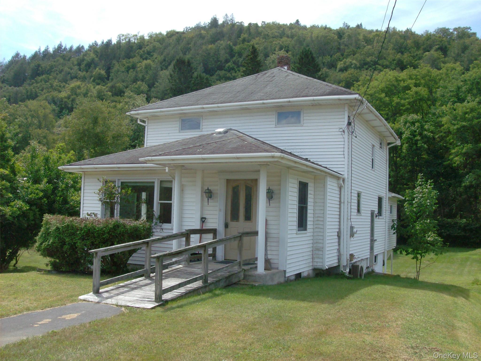 View of front of property with a forest view, a front yard, and a chimney