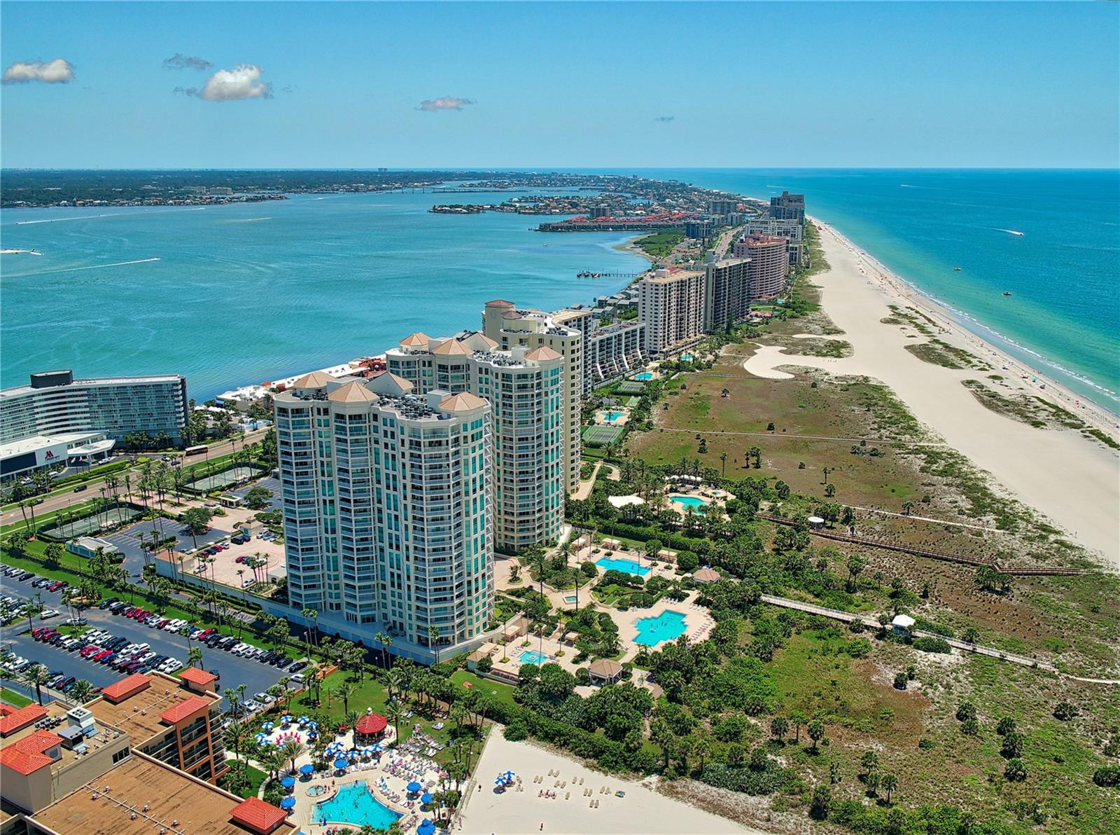Within the incomparable Watermark Grande on Sand Key Beach lies this 10th floor Northside Bellucia. Defined by spectacular and unobstructed Views of The Gulf of Mexico, Sand Key Park, Clearwater Pass, Downtown Clearwater, Both Bridges and the City’s Harbor you’ll find the panoramas are engaging, both day and night. Remarkable for its’ floor plan each and every room is encased by non-stop water vistas that glide seamlessly. The 3rd bedroom has been partially opened up, but can easily be put back. The open kitchen is integrated into a spacious  living and dining arena. Soft paint treatments, exquisite porcelain tile flooring resembling a beachy hardwood, and a timeless white kitchen await.  Terrace access is accessible from all, but one room. The Iconic Grandes offer an unparalleled Beach Existence encompassing 14 acres of unprecedented resort infused amenities inclusive of multiple pools, tennis courts, fitness centers, social and billiards rooms, and of course the legendary concierge services and 24 hr. guard gated security. NOW, HERE’S THE EXTRAORDINARY: UNDER THE BUILDING PARKING SPACE & A ROMAN CARPORT CONVEYS IN THE SALE OF THIS MAGNIFICENT CONDO HOME!!