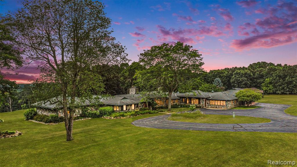 Traverse a paved, treelined drive to this captivating estate, elevated at the hilltop of a 23 acre parcel with tree-top views-all the way to Oxford! This unique and historic home is nothing short of spectacular from it's granite architecture and copper gutters housing 5800 sq feet of first floor living, spacious rooms impacted by paneled walls, huge windows, black walnut, slate and tile floors and complementing granite fireplaces... 4 in total. Designed for entertaining, this home is a journey. A gracious entrance welcomes you into a huge living room with walls of windows and great views. A kitchen Emeril would be proud of... 7 foot granite island with Viking cooktop and grill, all stainless steel appliances and lovely breakfast dining with Mimosa bar. A dining room for 30+ is a banquet in itself with patio doors leading out to the yard. The original laundry room was altered to a full utility area, and a 4 car drywalled and heated garage was added. The owner's suite is a symphony in size and quality, nearly 1200 sq ft of your own oasis. The bedroom is private with access to the raised patio for relaxing views and sunshine. A corridor of cherry closets opens into huge bath, indescribable with granite counters, huge whirlpool tub, walls of mirrors, tile shower and a private laundry and leading to a massive dressing room with built-ins, island, jewelry safe and cherry woodwork throughout. A 2nd suite with walk in closet and tile bath enjoys a private entrance, and a 3rd bedroom, full ceramic bath and study with gas fireplace complete this level. The lower level has been freshly renovated with luxury vinyl tile, new carpeting and features a family room with gas fireplace, 2nd kitchen, 2 game rooms, wine cellar, utility with 3 of 4 furnaces, bath and laundry.  Meticulously maintained and beautifully landscaped grounds feature trails, a converted cedar horse barn previously used for stables, hay storage, tack, wash stall, storage and clasrooms, and a remote 3 car garage!