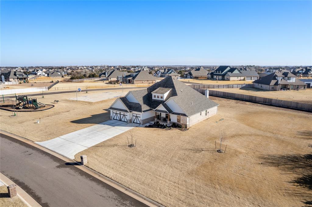 Welcome home to this gem where space, style, and location come together beautifully in Deer Creek schools! Sitting on an oversized corner lot right next door to the community park and sports courts, this home offers room to spread out both inside and out! With 3,700 total square feet (including 3,350 sq ft of indoor living plus 350 sq ft of outdoor living), this thoughtfully designed home features 5 bedrooms, 3.5 bathrooms, a large bonus room, and a 3-car garage with an in-ground storm shelter. The heart of the home is the stunning great room, showcasing a coffered ceiling, gas fireplace wrapped in stacked stone to the ceiling, wood-look tile floors, and oversized windows that flood the space with natural light. The kitchen is equally impressive with custom cabinets to the ceiling, glass-front uppers and lighting, 3 cm quartz countertops, stainless steel appliances, and a spacious corner pantry. The primary suite is a true retreat with a sloped ceiling detail and a spa-like bathroom featuring a Jetta Whirlpool tub, walk-in shower, dual vanities, and a HUGE walk-in closet that connects directly to the laundry room (a favorite feature for a reason!) Step outside to enjoy the covered back patio, complete with a wood-burning fireplace, gas line for grilling, and TV hookup - your new favorite spot for game days or cozy evenings. Additional highlights include a tankless water heater, whole-home air purification system, and R-44 insulation, offering comfort and efficiency year-round. This home checks all the boxes - space, location, and quality finishes in an award winning school district. Schedule your showing today!